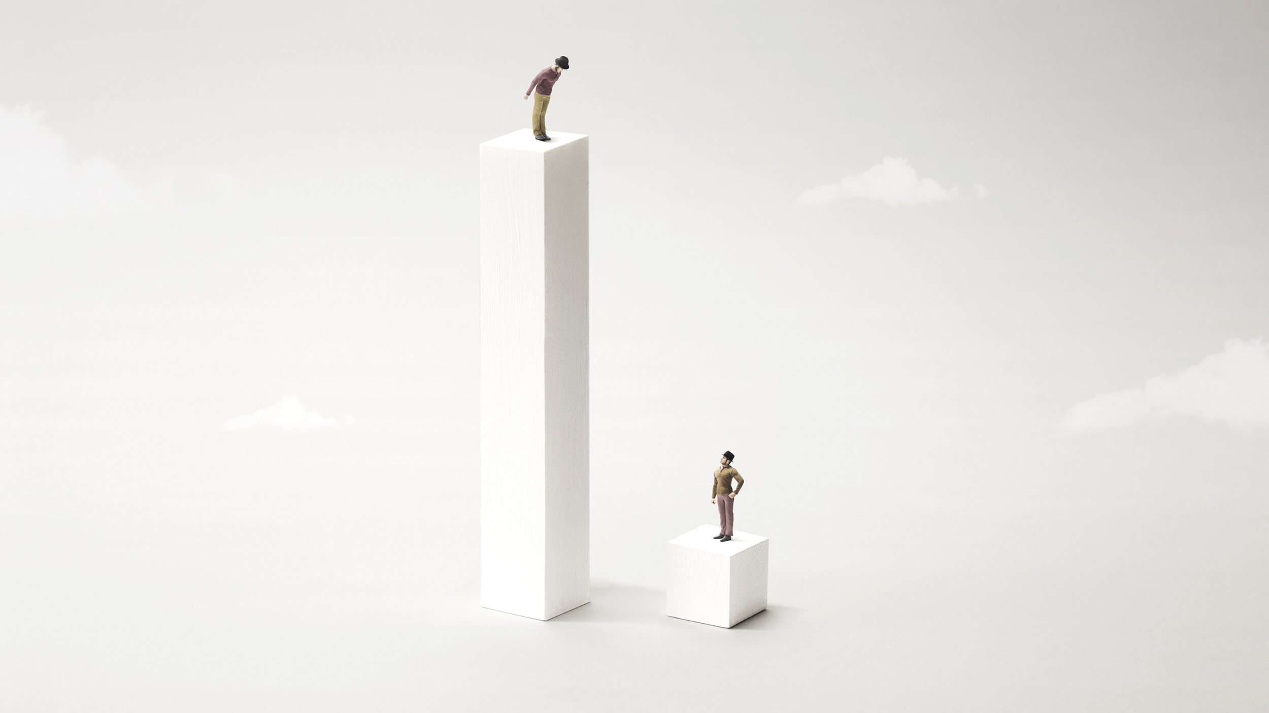 Two miniature figures are standing on white rectangular blocks of different heights in a minimalistic setting with a pale background. One figure is standing on the smaller block, looking up at the other figure on the taller block.
