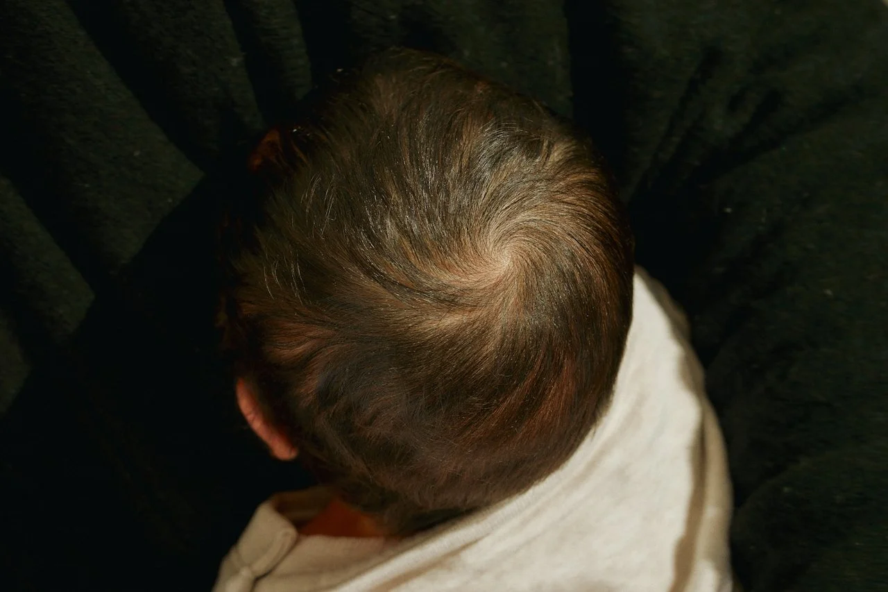 Top view of a baby's head with brown hair.