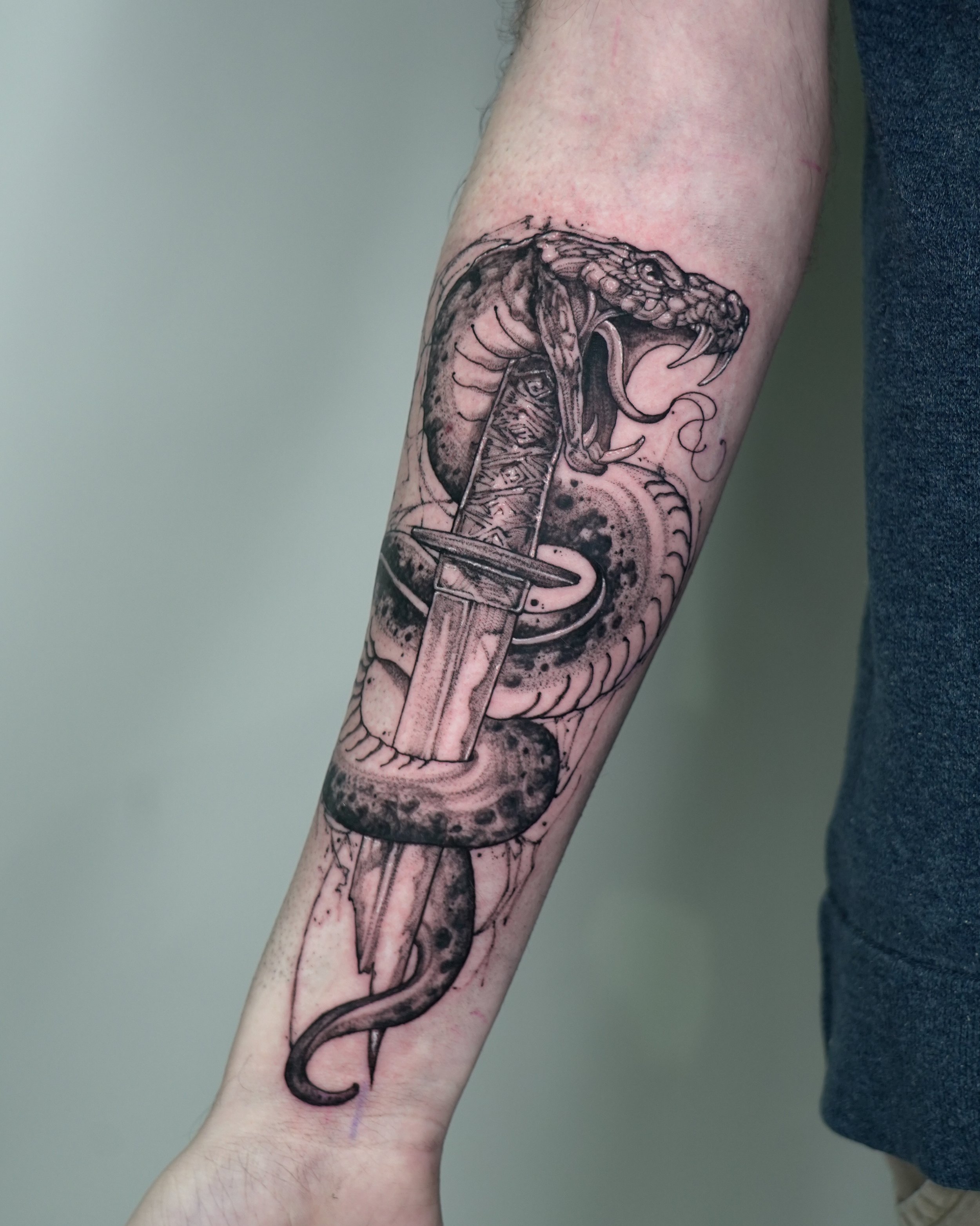 Black and grey tattoo of a snake coiled around a katana on forearm by Jay C Tattoo, Brighton tattoo artist, UK
