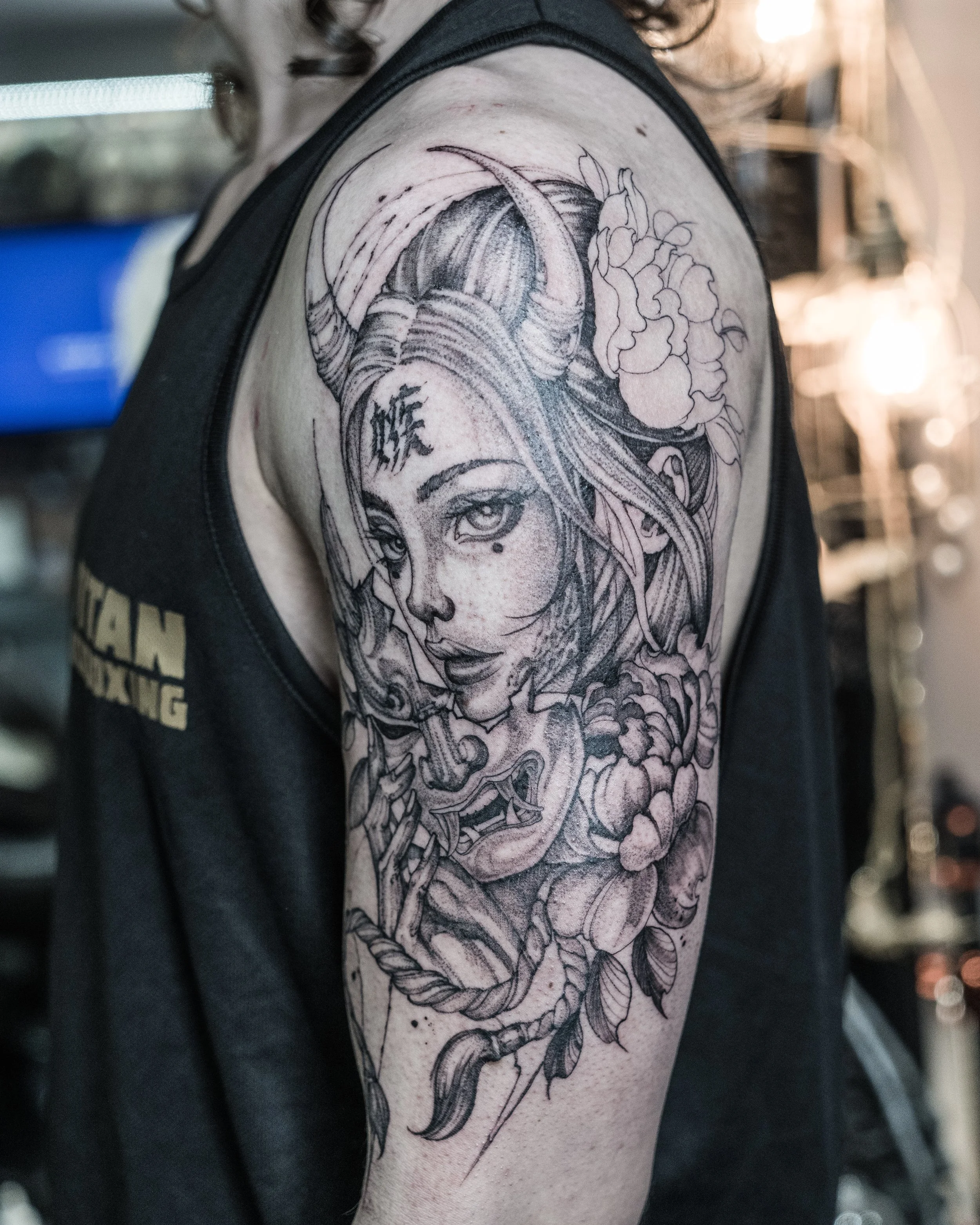 Black and grey tattoo of a Geisha woman’s face with horns and floral elements by Jay C Tattoo, Brighton and Hove tattoo artist, UK
