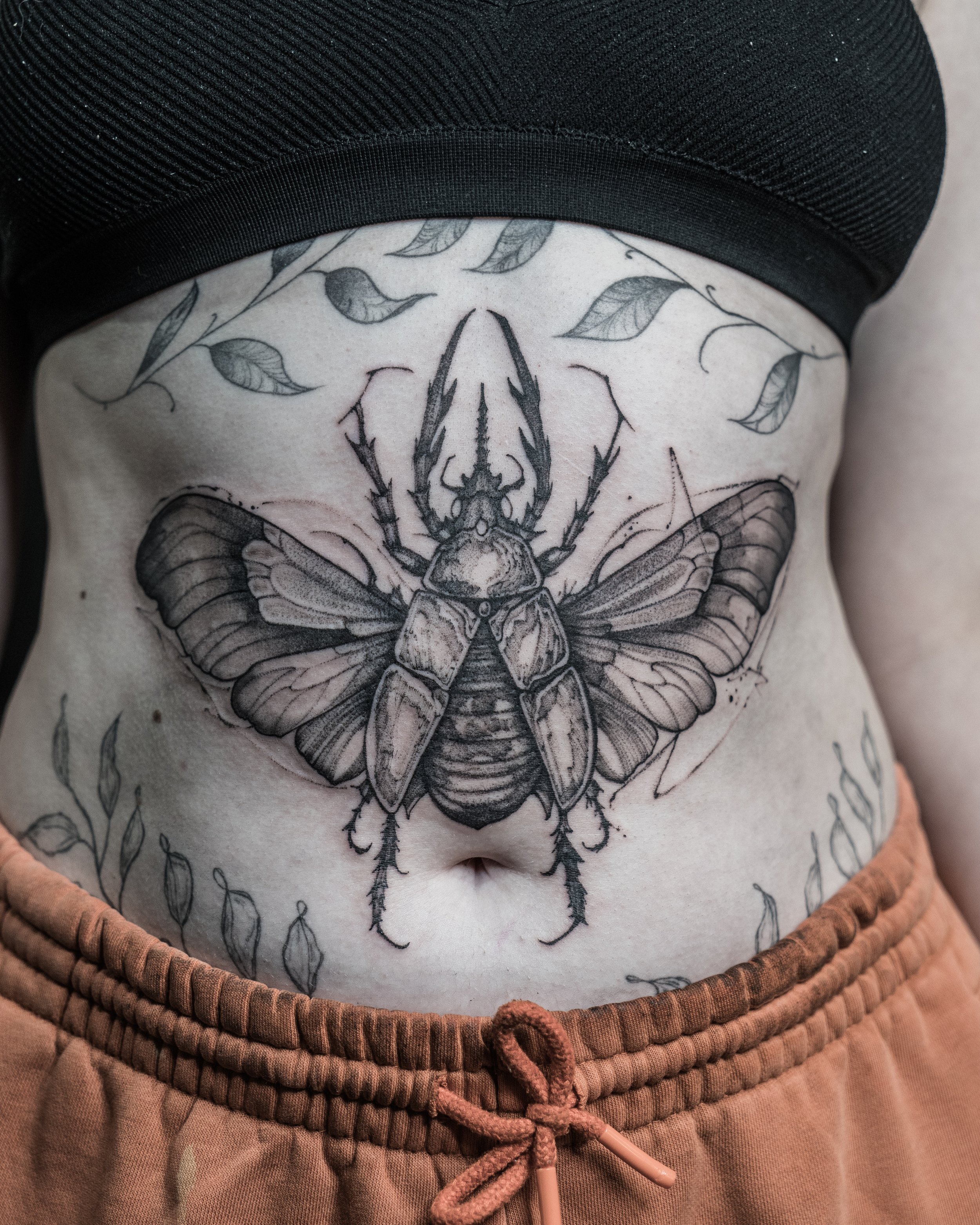 Black and grey beetle tattoo with detailed wings and leaves on stomach by Jay C Tattoo, Brighton tattoo artist, UK
