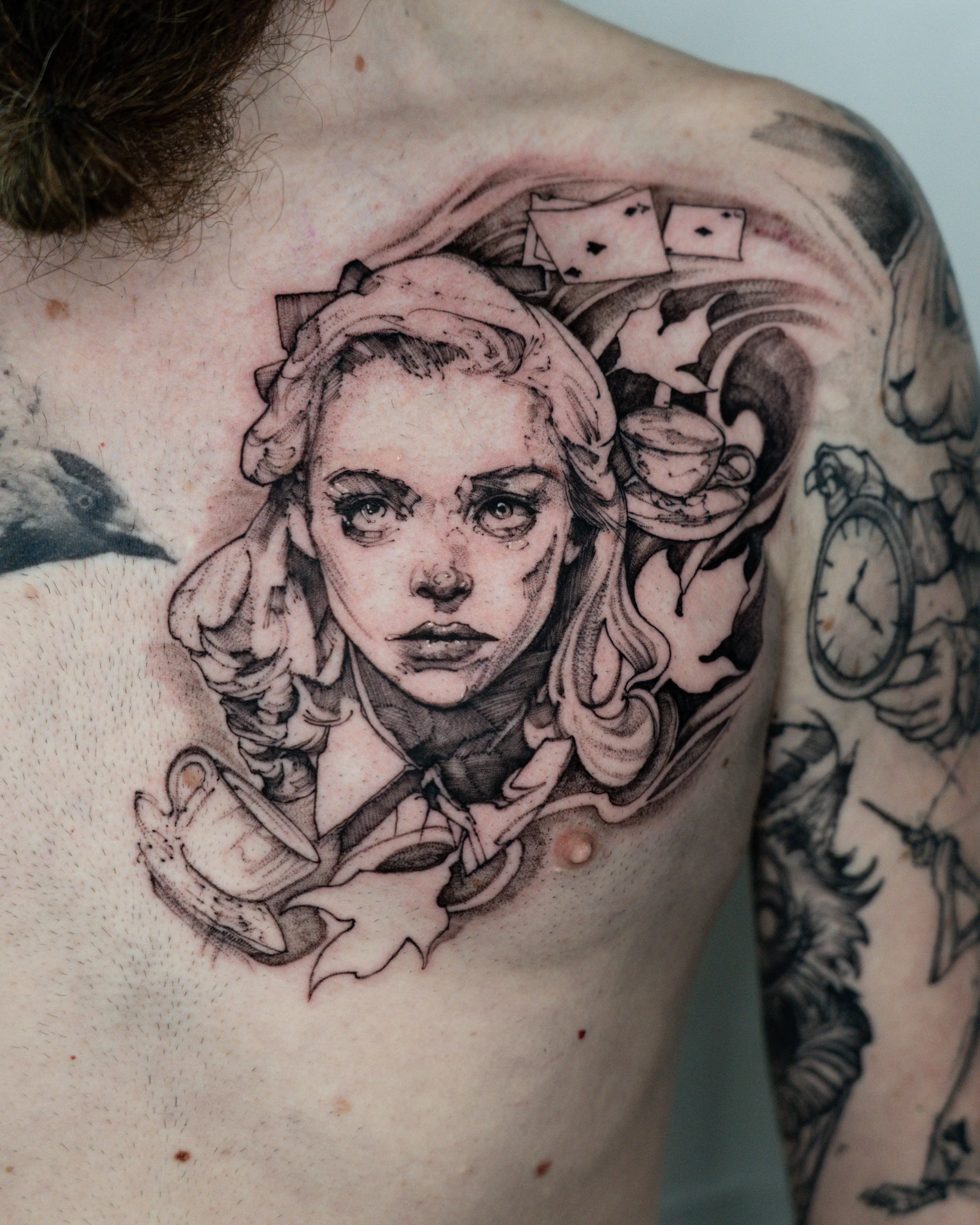 Black and grey chest tattoo of Alice in wonderland with playing cards, clock and decorative elements by Jay C Tattoo, Brighton and Hove tattoo artist, UK