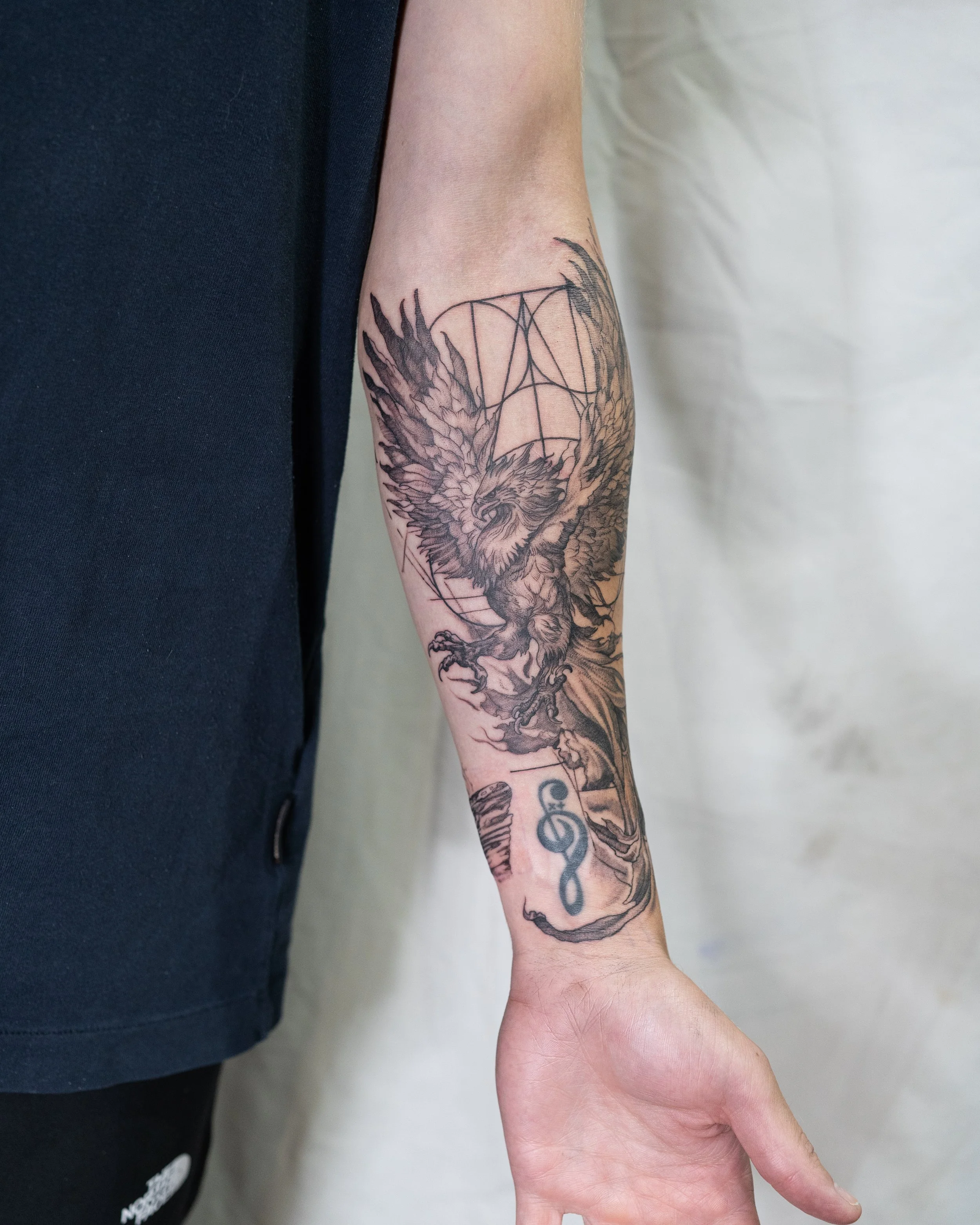 Fine line tattoo of a Phoenix with outstretched wings, geometric design and infinity symbol on wrist by Jay C Tattoo, Brighton and Hove tattoo artist, UK
