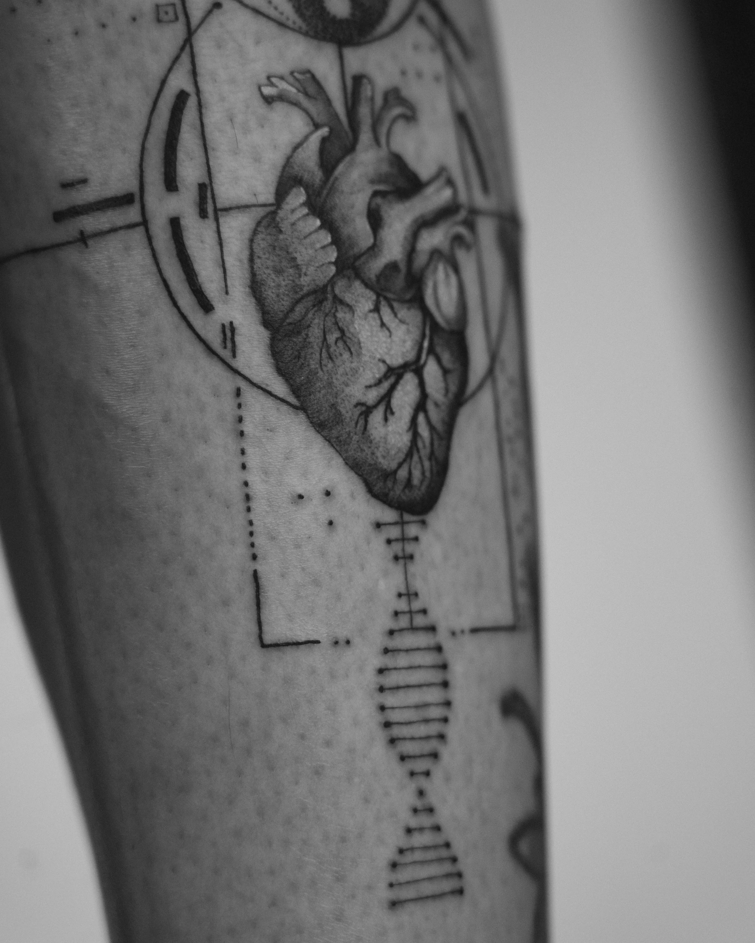 Black and grey realistic human heart tattoo with detailed arteries and geometric lines by Jay C Tattoo, Brighton tattoo artist, UK
