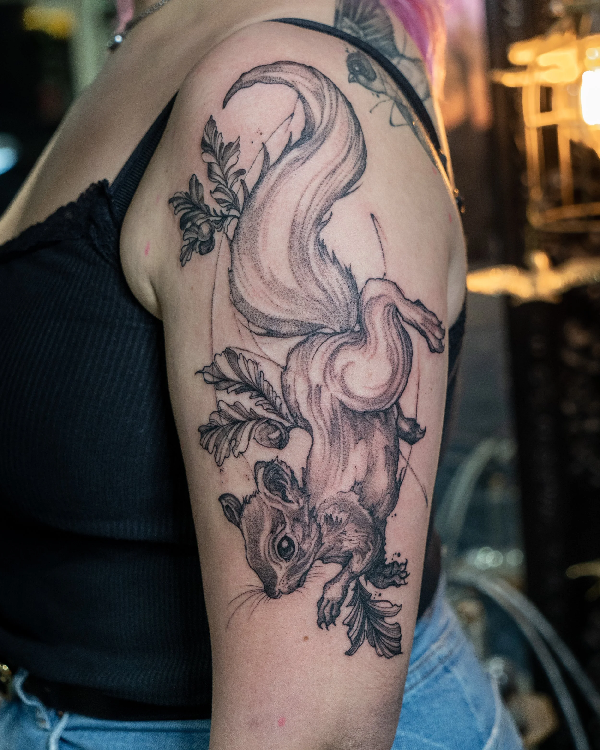 Black ink tattoo of a squirrel with leaves on upper arm by Jay C Tattoo, Brighton tattoo artist, UK
