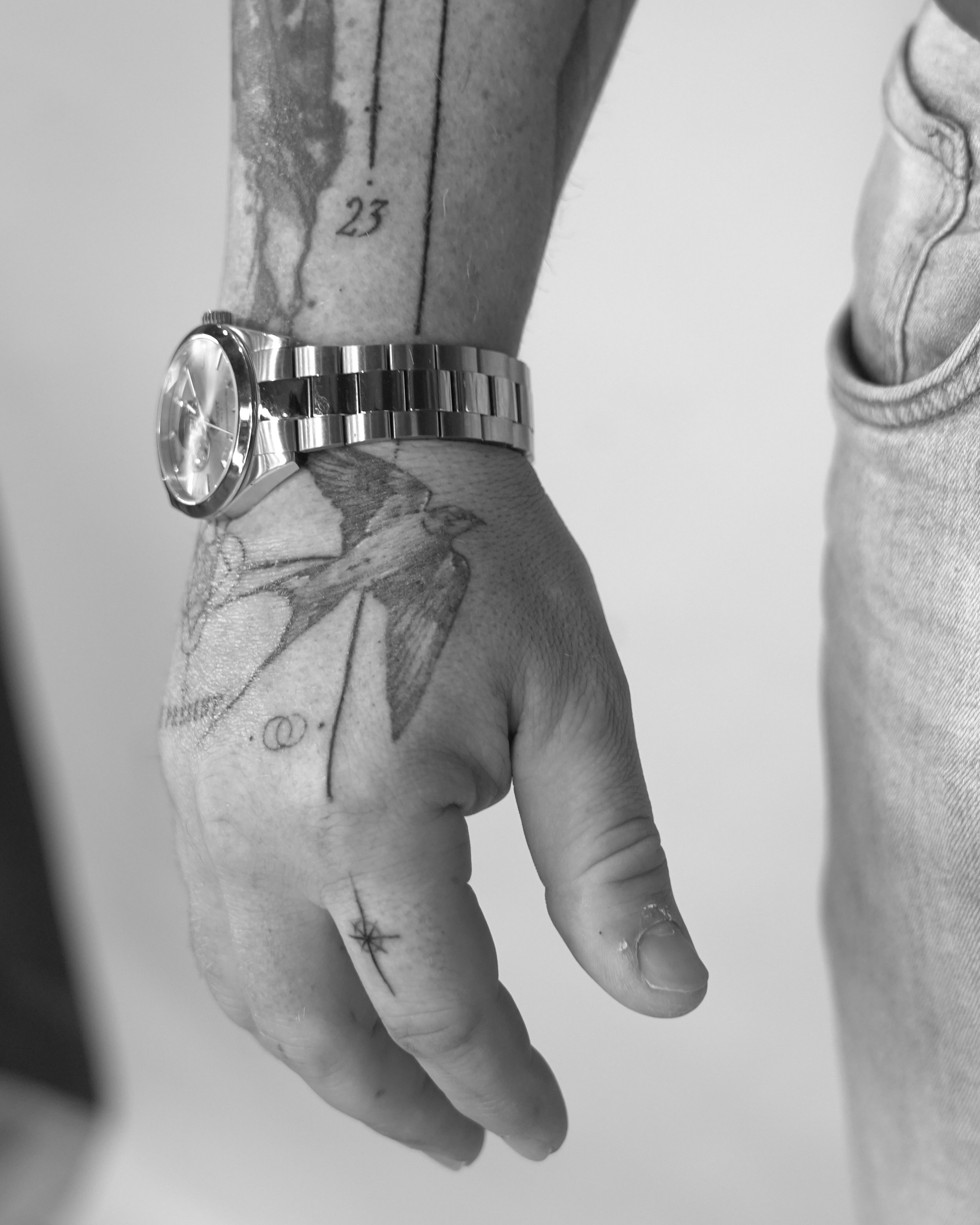 Close-up of tattooed hand with bird, star and number 23 tattoos by Jay C Tattoo, Brighton and Hove tattoo artist, UK
