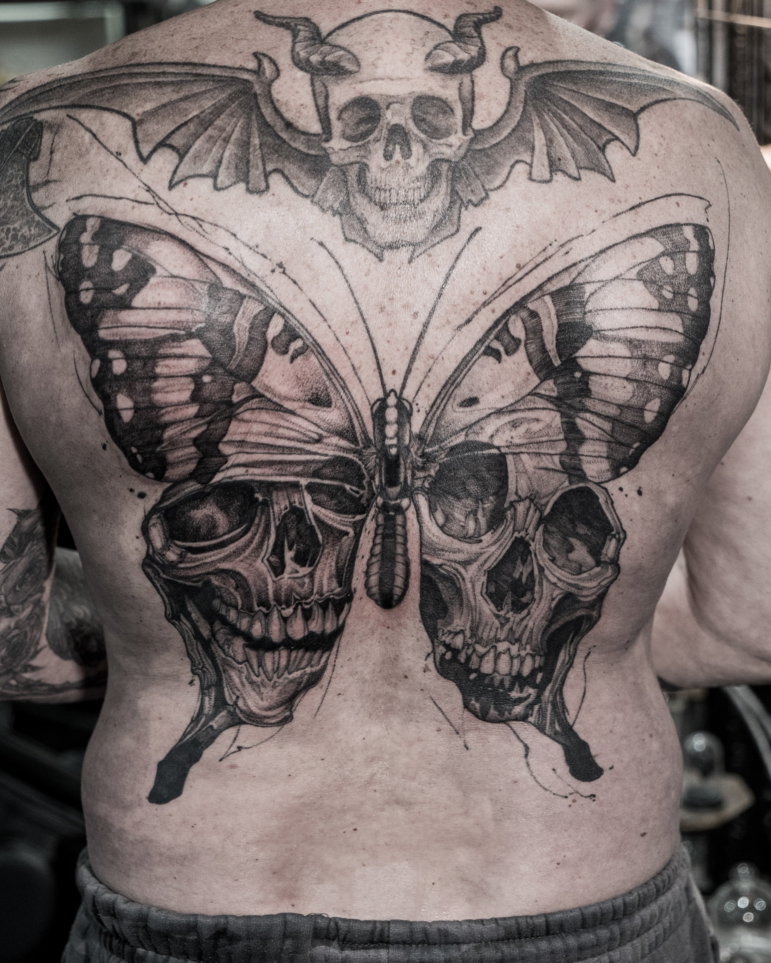 Black and grey back tattoo of a butterfly with skull wings and central skull by Jay C Tattoo, Brighton tattoo artist, UK
