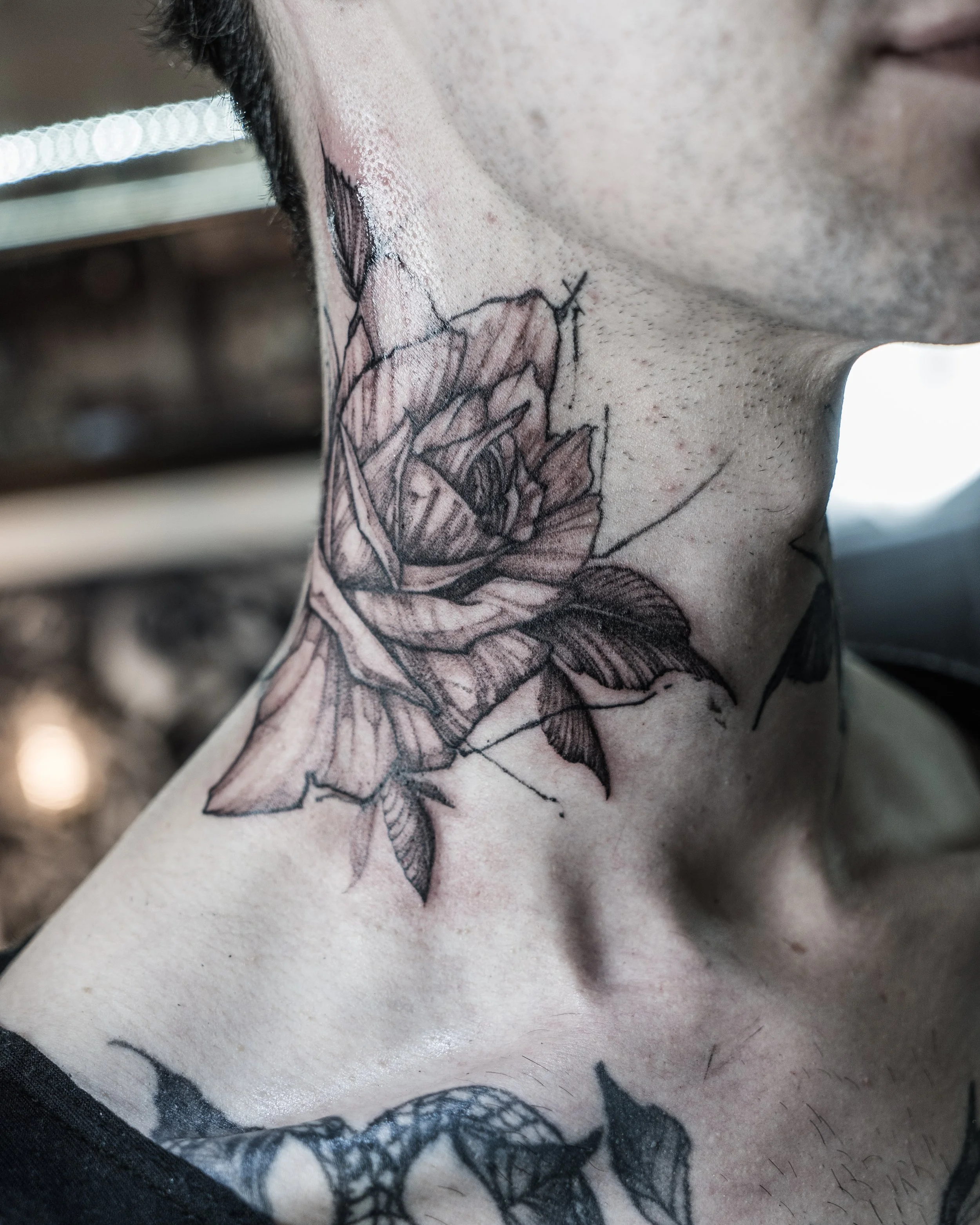 Close-up of black ink rose tattoo with leaves on neck and shoulder by Jay C Tattoo, Brighton tattoo artist, UK
