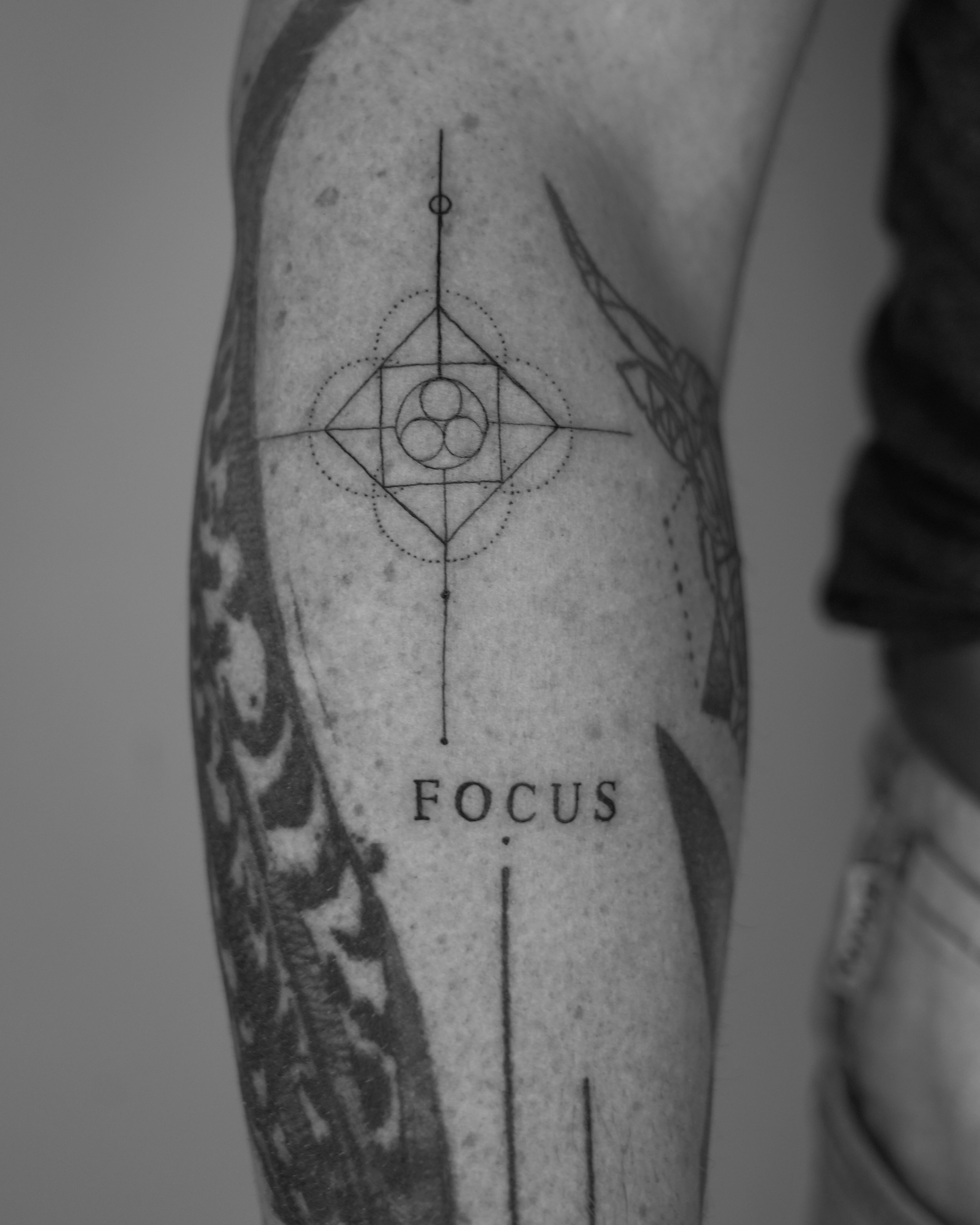 Fine line geometric tattoo with circles and lines and the word ‘FOCUS’ on arm by Jay C Tattoo, Brighton and Hove tattoo artist, UK
