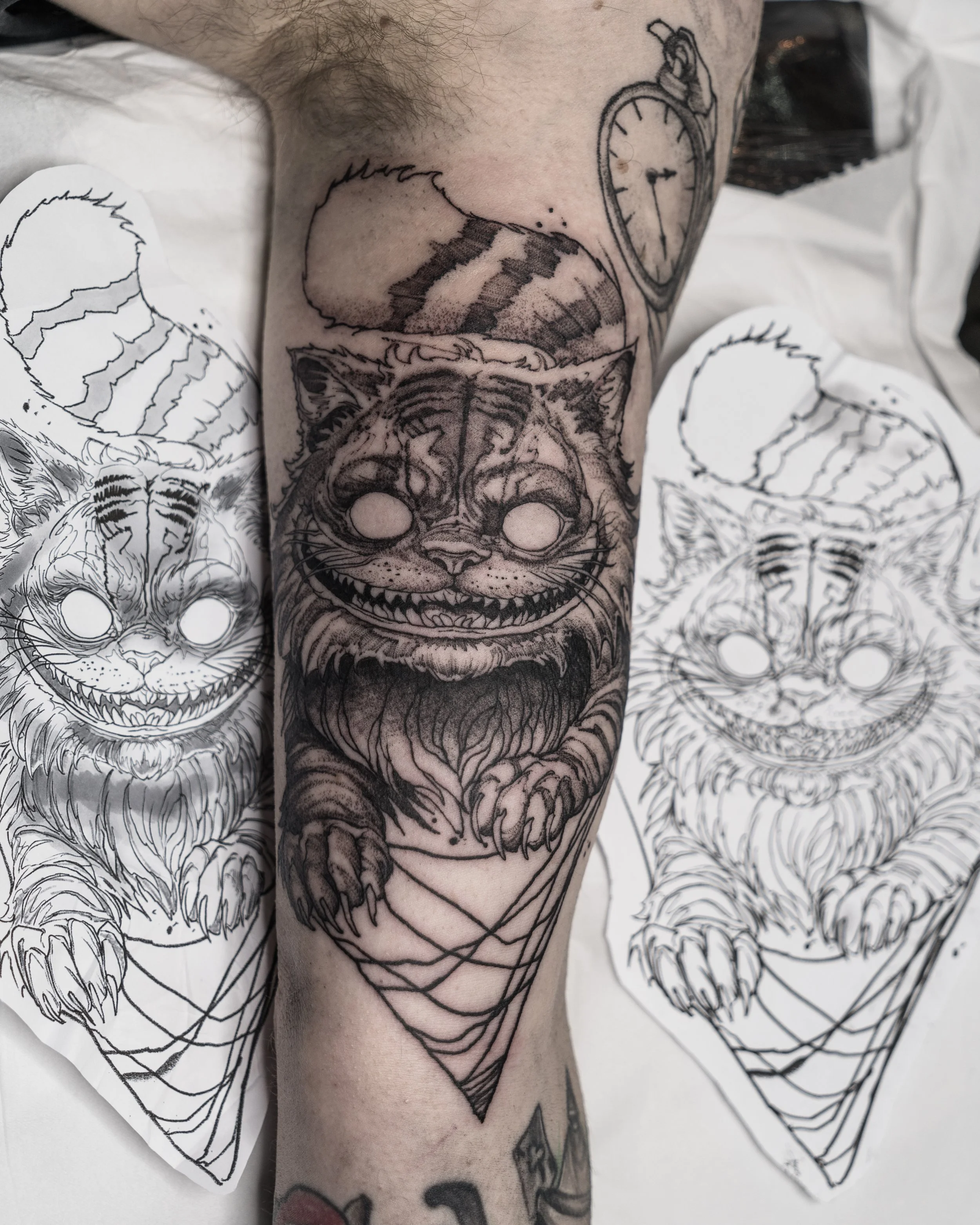 Black and grey Cheshire Cat tattoo with pocket watch and cloud from Alice in Wonderland by Jay C Tattoo, Brighton and Hove tattoo artist, UK