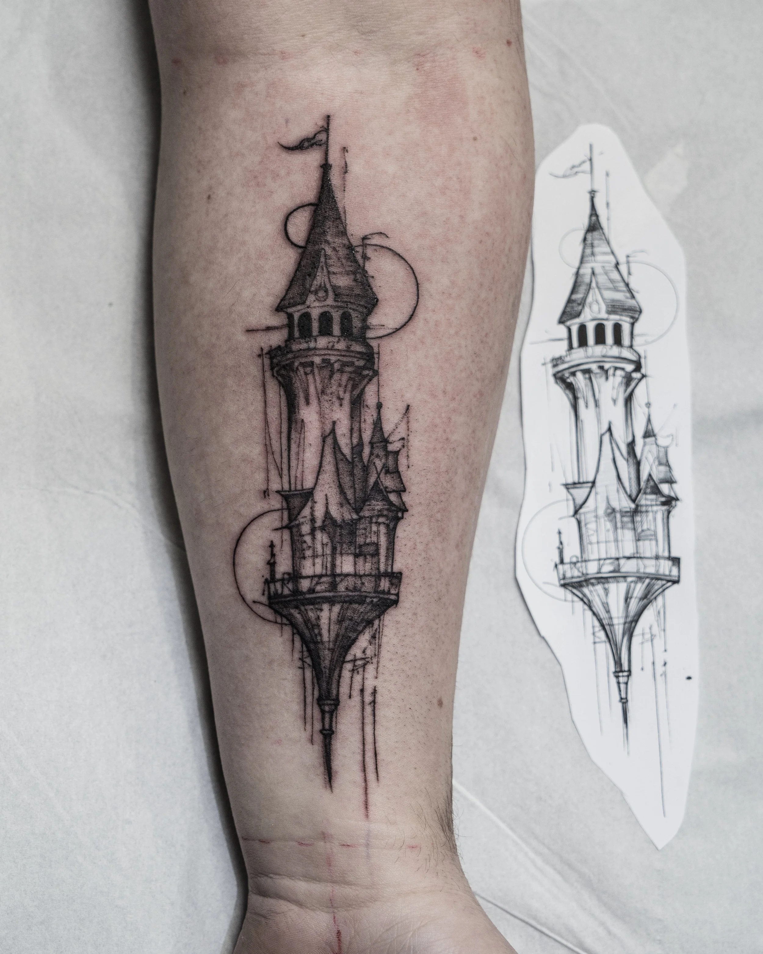 Black ink tattoo of a tall fantasy castle on forearm with original sketch by Jay C Tattoo, Brighton and Hove tattoo artist, UK
