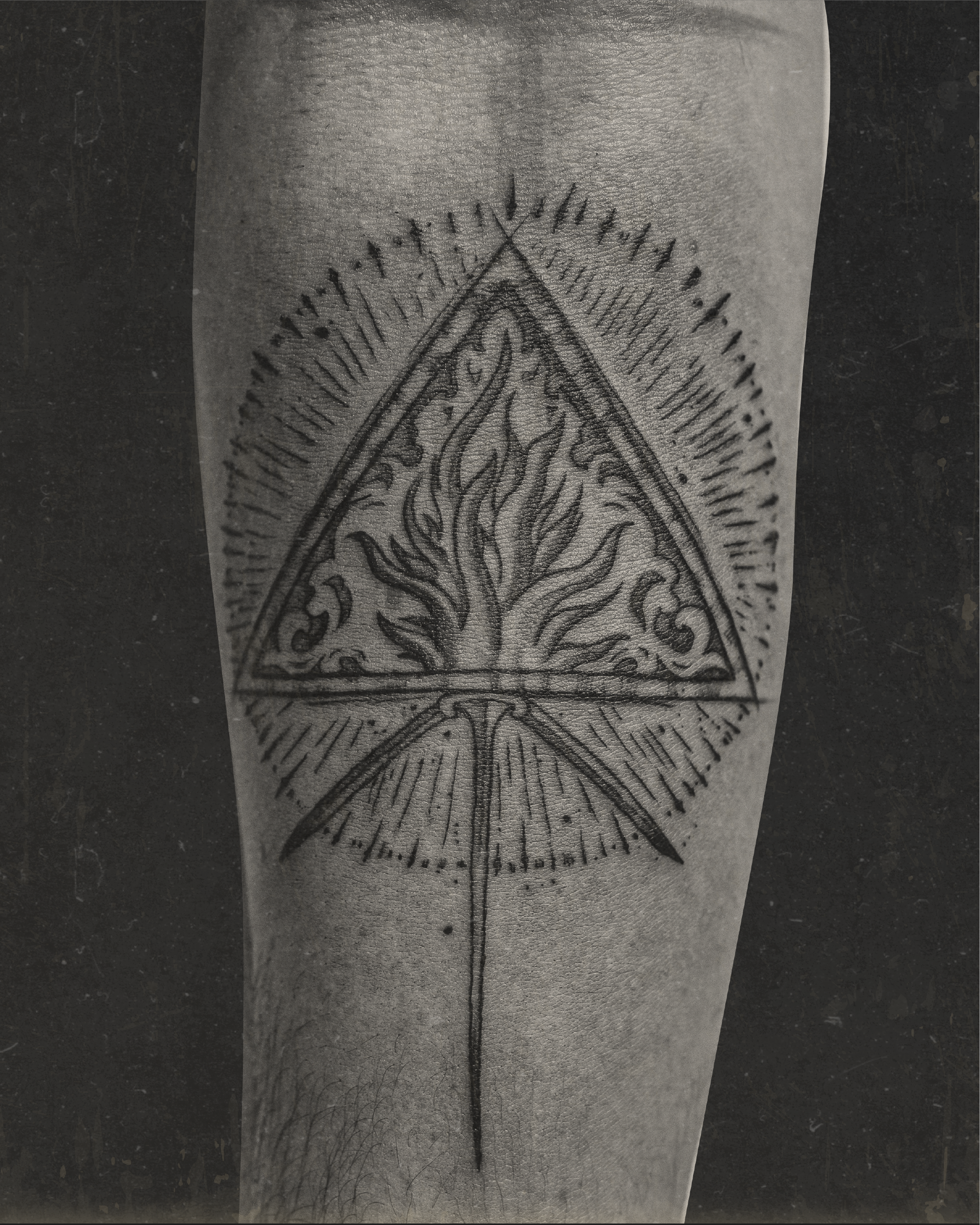 Black and grey tattoo of a triangle with flames inside on arm by Jay C Tattoo, Brighton tattoo artist, UK