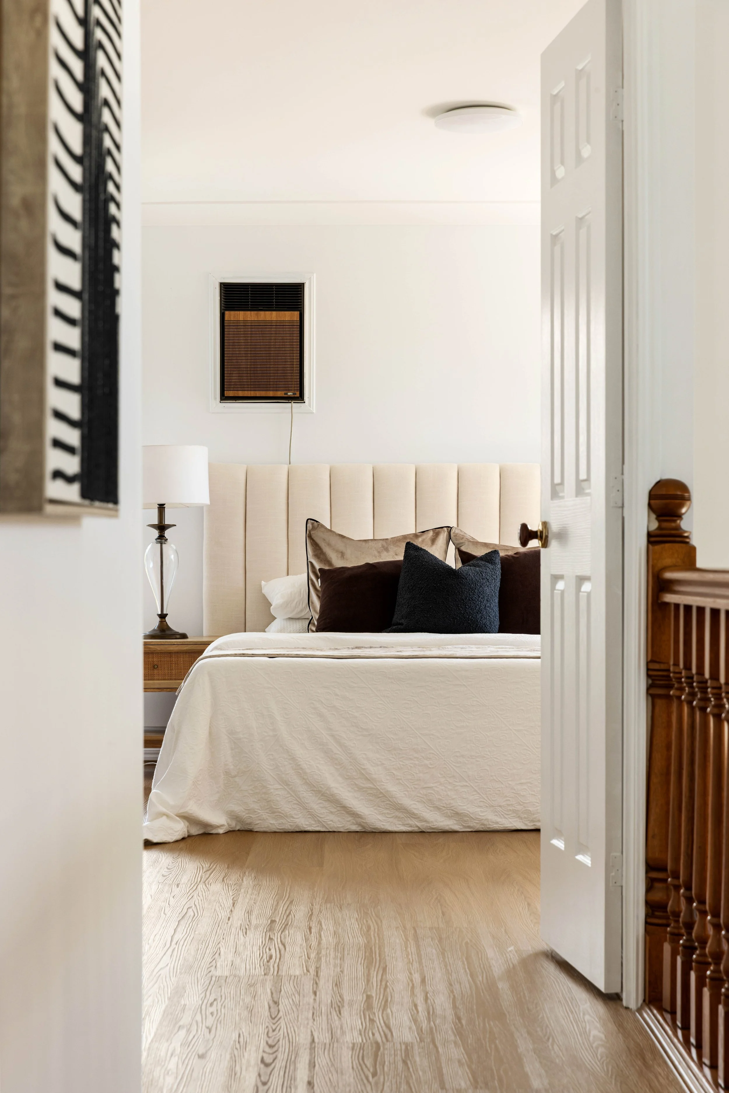 A bedroom with a bed, pillows, a nightstand, a lamp, a window with shades, and a door partially open.
Professional real estate photography in Brisbane, highlighting a modern bathroom with natural light, clean finishes, and a spacious layout.