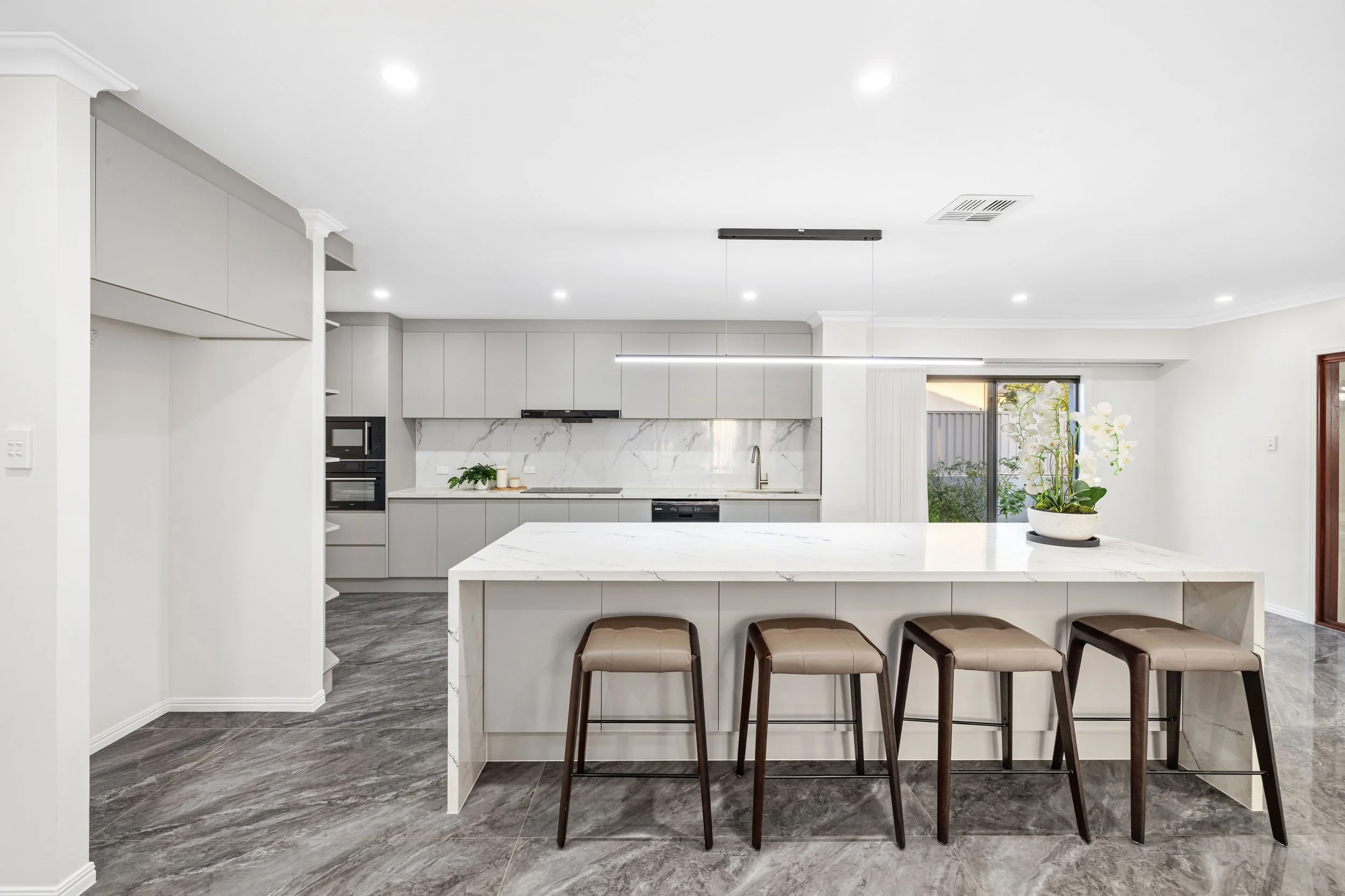 Modern kitchen with white cabinets, marble backsplash, and island with four barstools