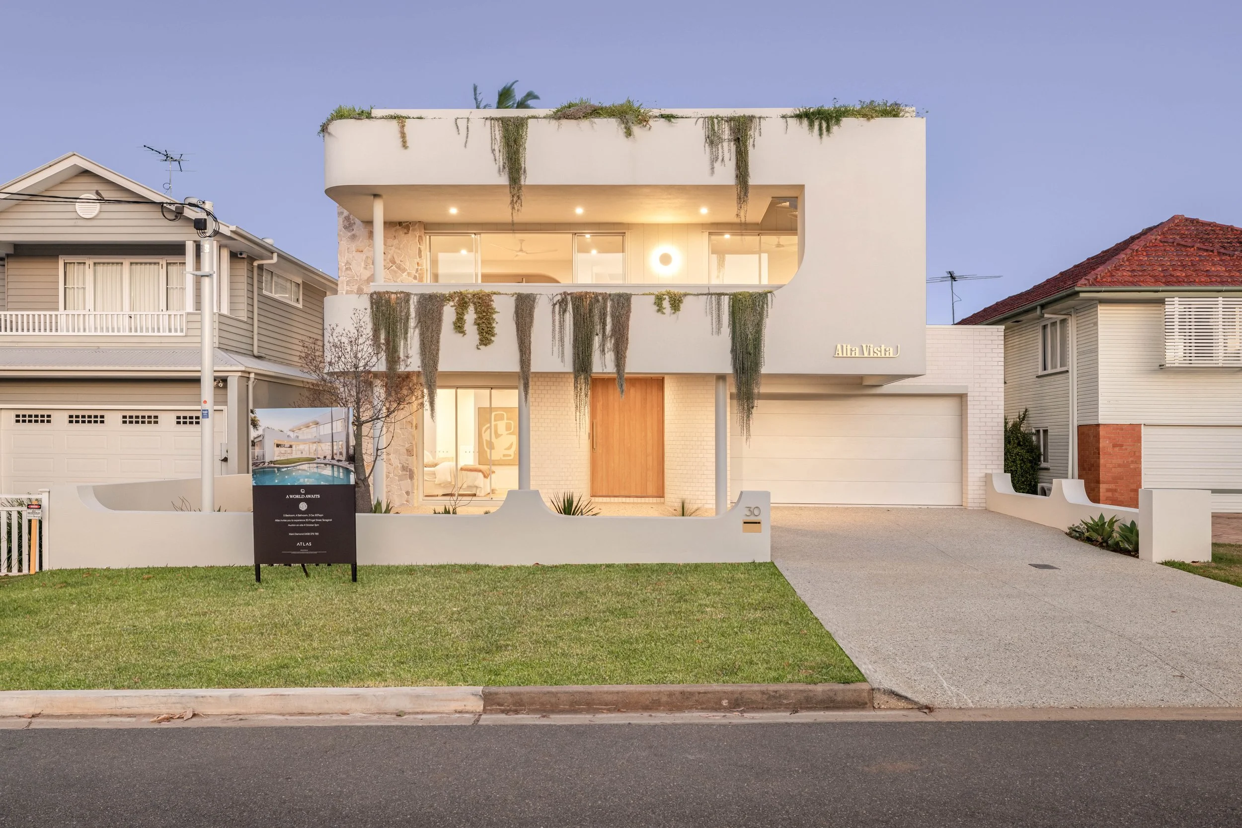 Modern two-story house with white exterior, large glass windows, and hanging greenery on the balcony. Professional real estate photography in Brisbane, highlighting a modern bathroom with natural light, clean finishes, and a spacious layout.