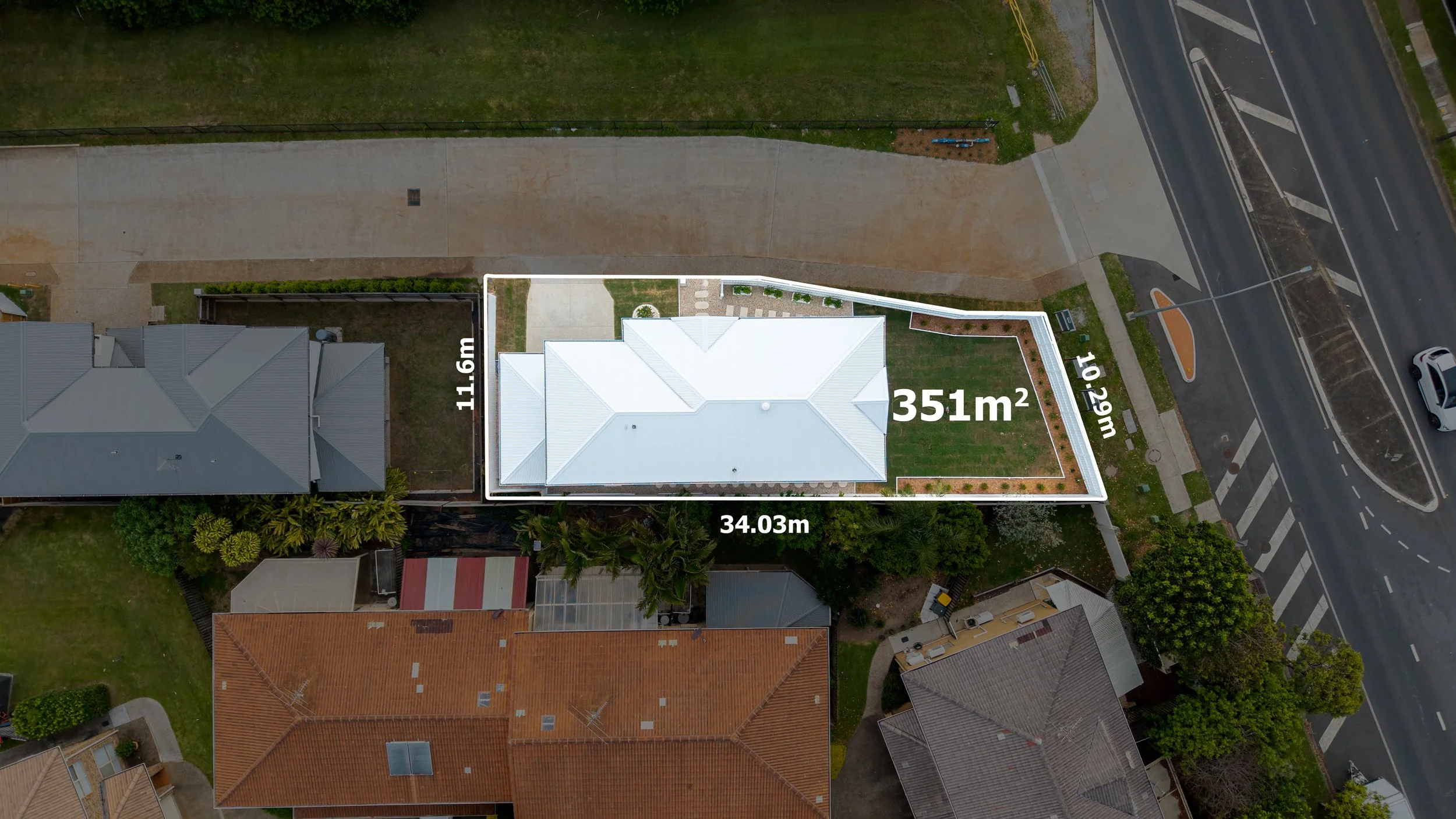 Aerial view of a residential property with outlined dimensions and area, showing a house, yard, neighboring houses, and surrounding streets.