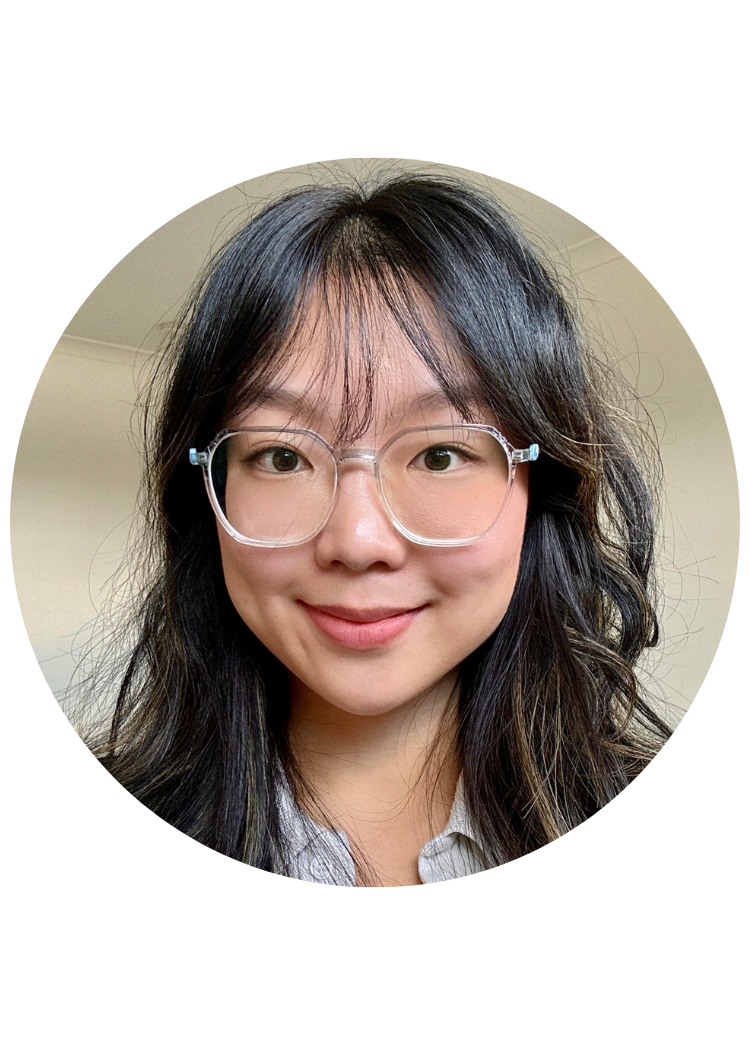 A young woman with shoulder-length wavy black hair, wearing clear glasses and a white shirt, smiling at the camera.