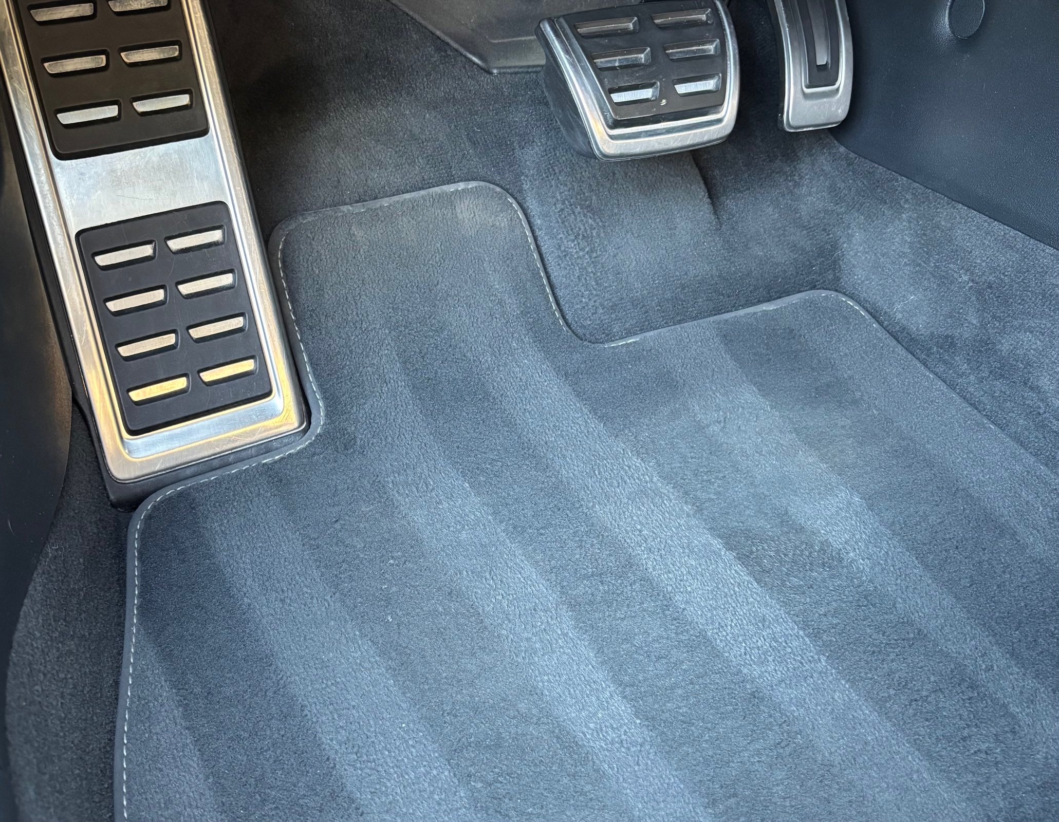 Tapis de voiture noire avec pédales en métal.