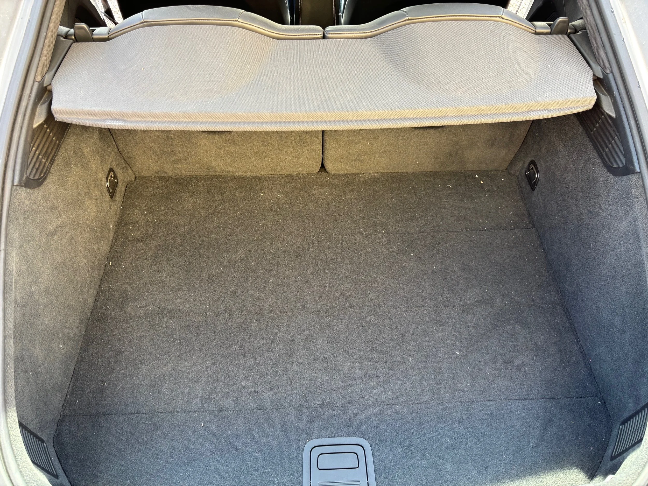 Intérieur d'un coffre de voiture vide avec tapis en tissu gris et rehauts latéraux