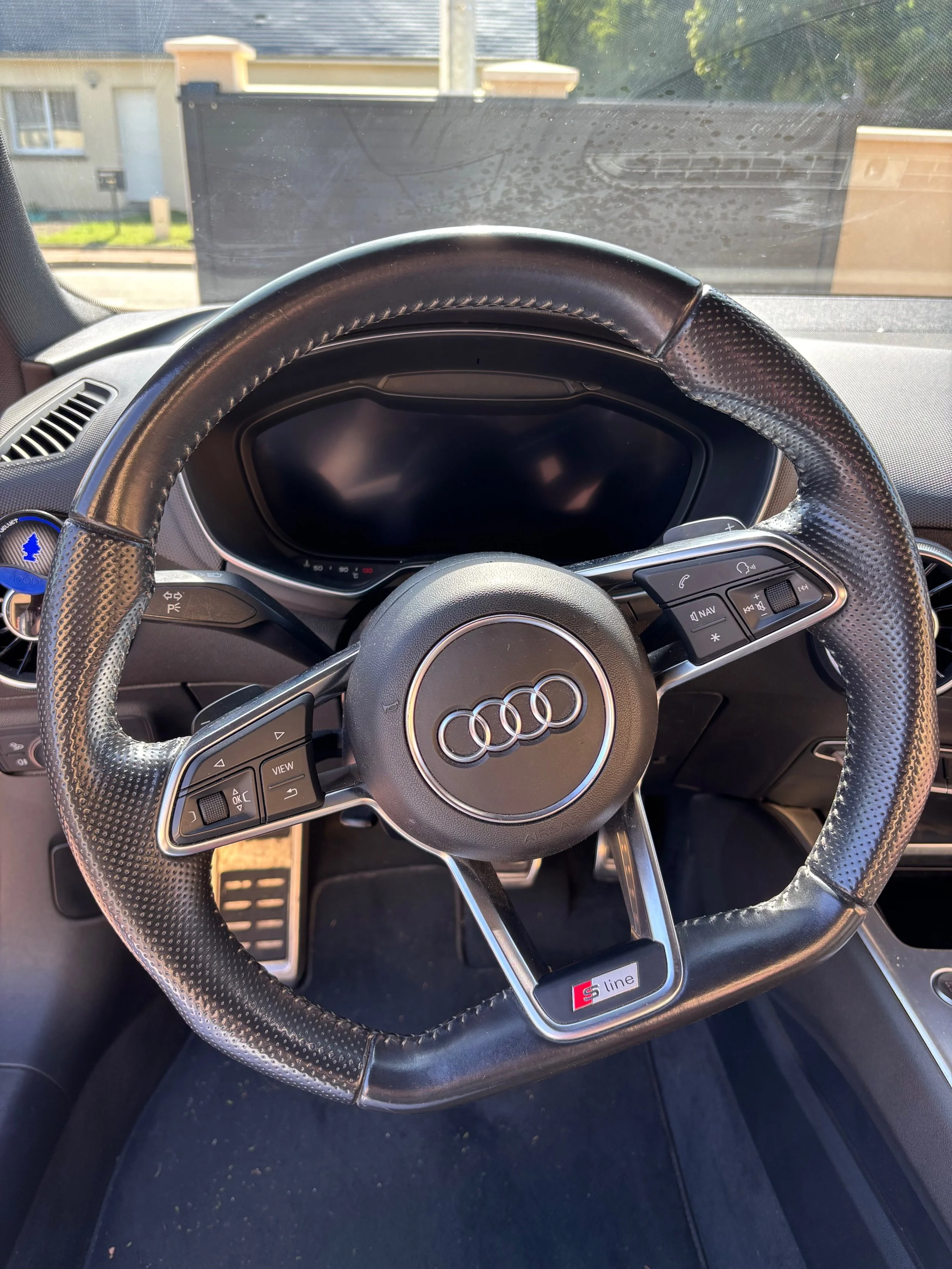 Volant de voiture Audi avec tableau de bord numérique et commandes intégrées, vue de l'intérieur du véhicule.