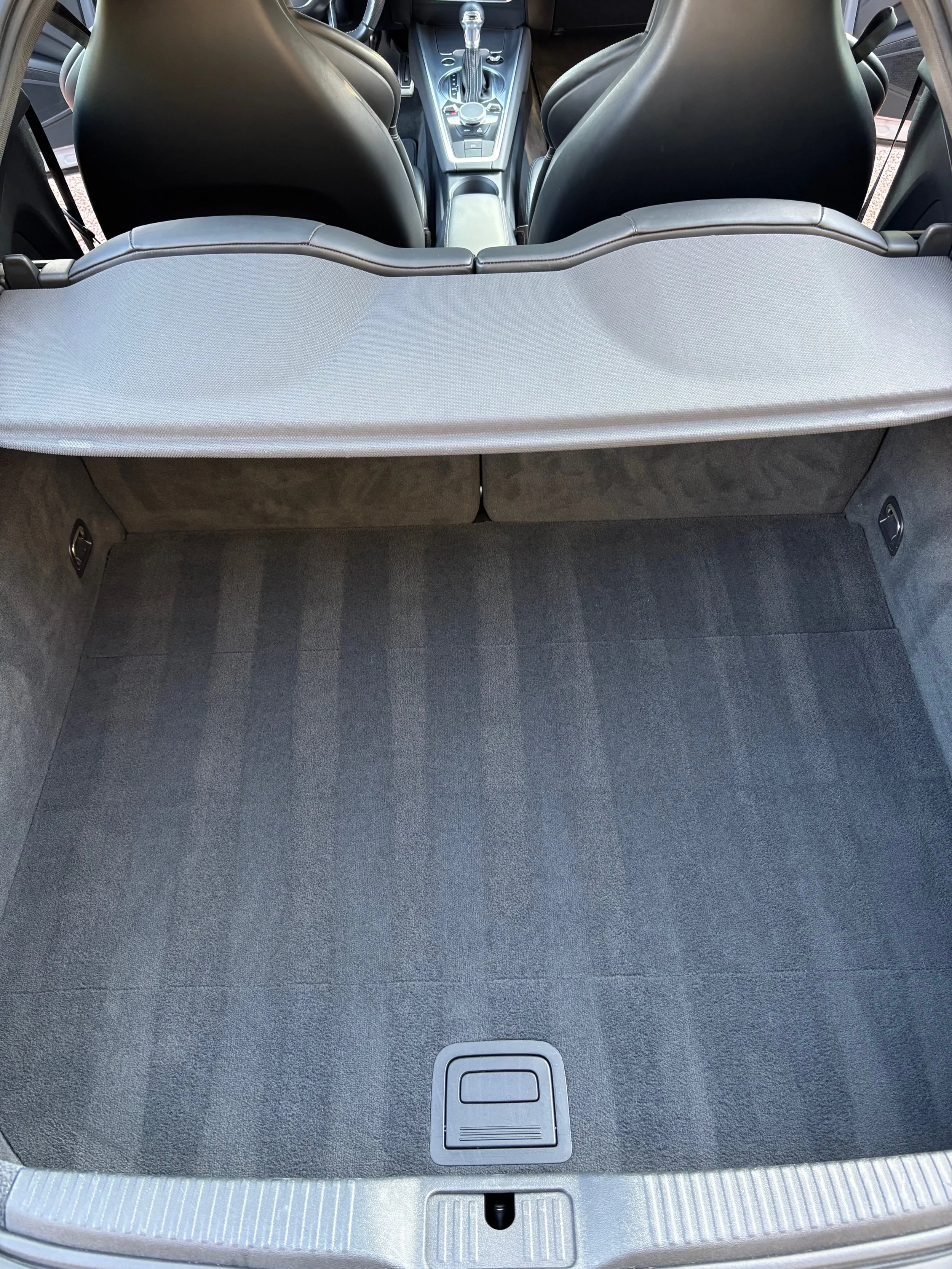 L'espace de coffre de voiture vide avec un tapis gris et une barre de séparation