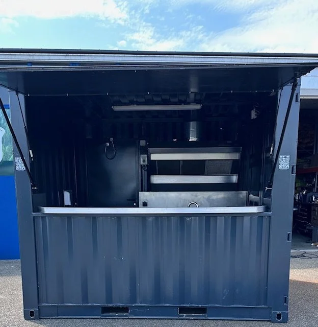 A food truck with an open serving window, displaying an industrial kitchen setup inside.
