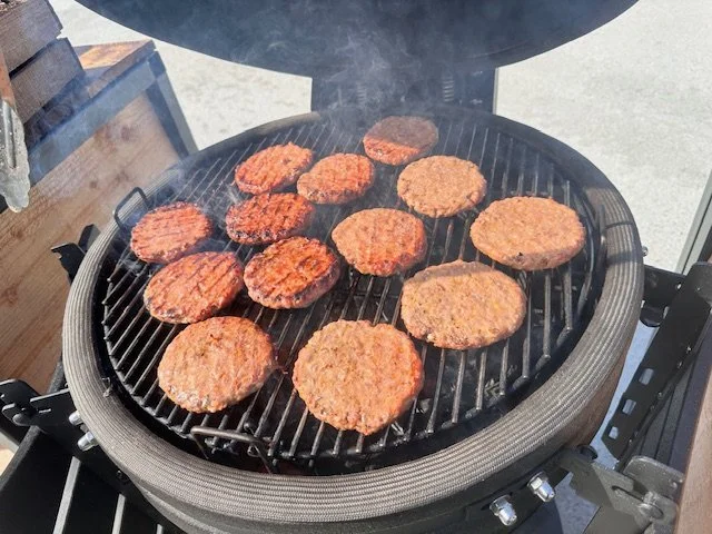 Hamburger patties cooking on a round outdoor grill