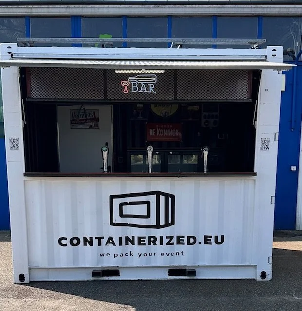 Outdoor event bar with three beer taps and a sign reading "CONTAINERIZED.EU" and "we pack your event."