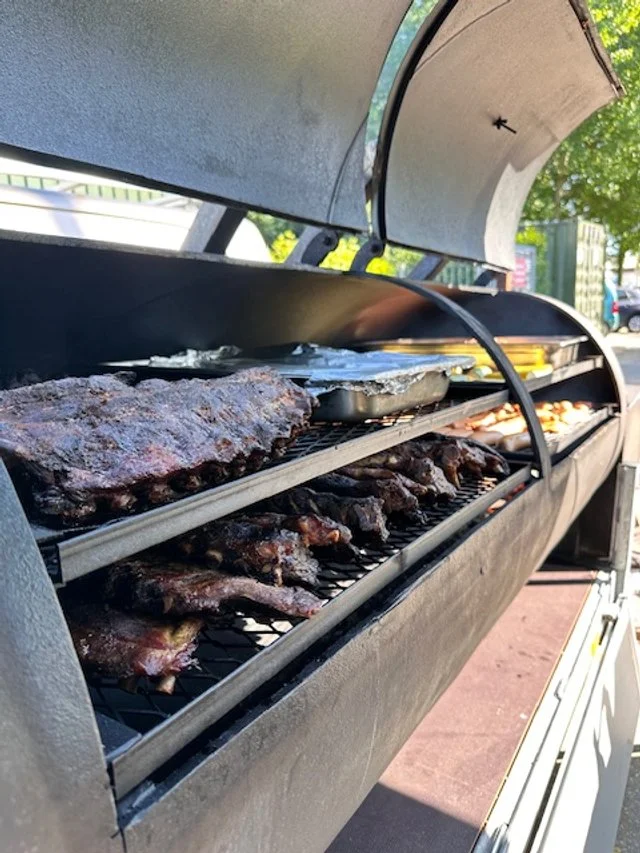 Close-up of a barbecue grill with various meats and food items cooking inside.