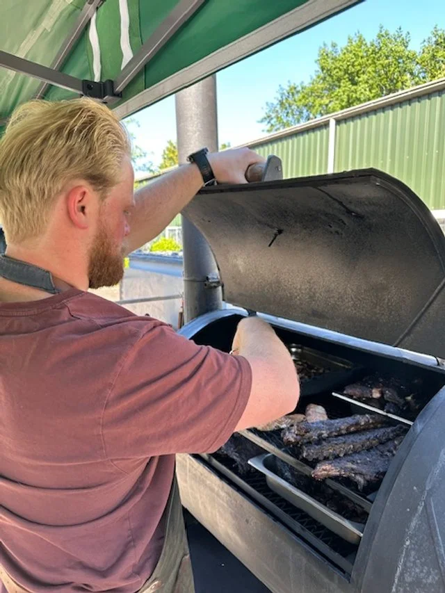 Man grilling ribs on a barbecue grill outdoors during daytime.