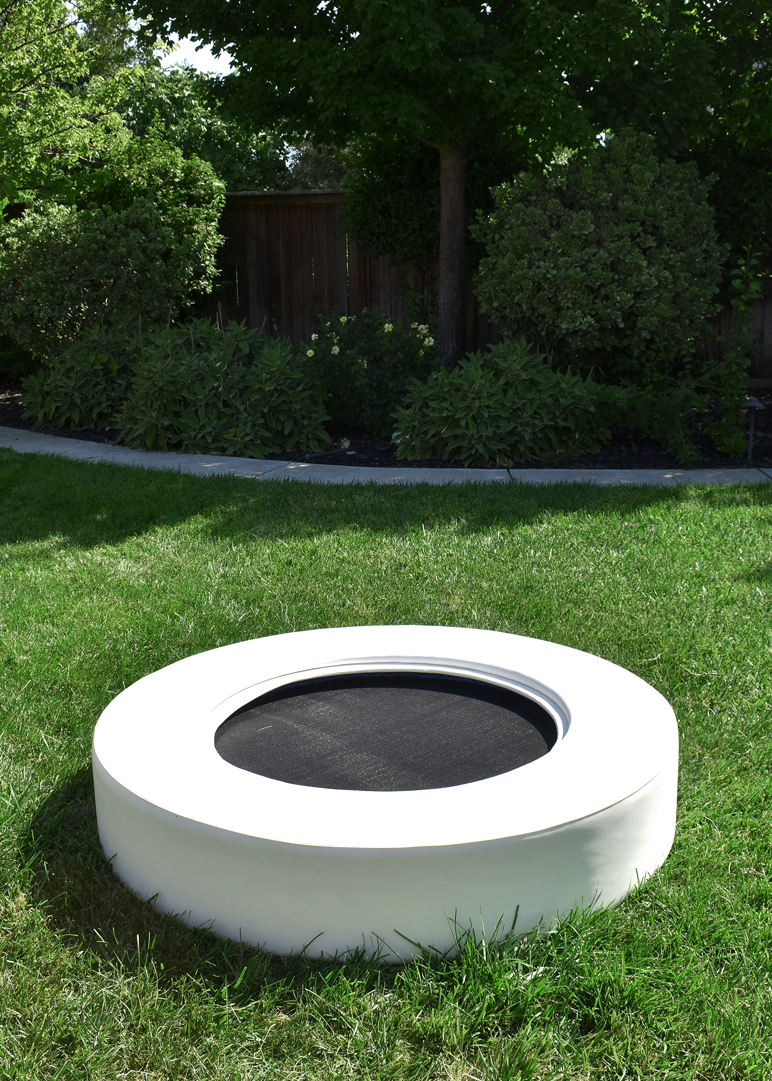A white trampoline on grassy area.