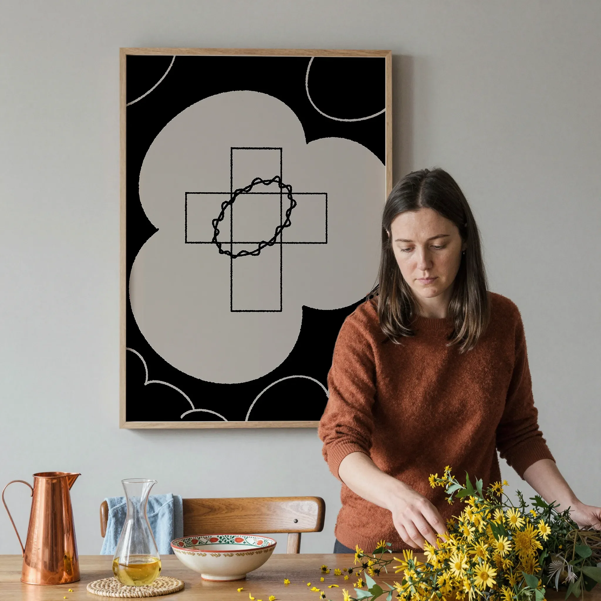 A Christian wall art print featuring cross art poster crown of glory design, shown in a dining space with a person arranging the table with flowers and tableware.