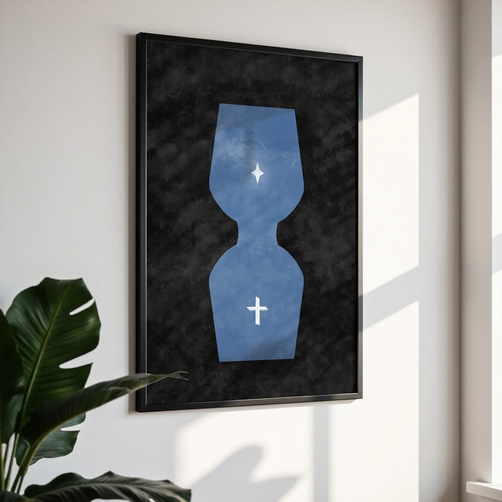 Framed wall art in a simple black frame, photographed from an angled view against a white wall with direct sunlight.