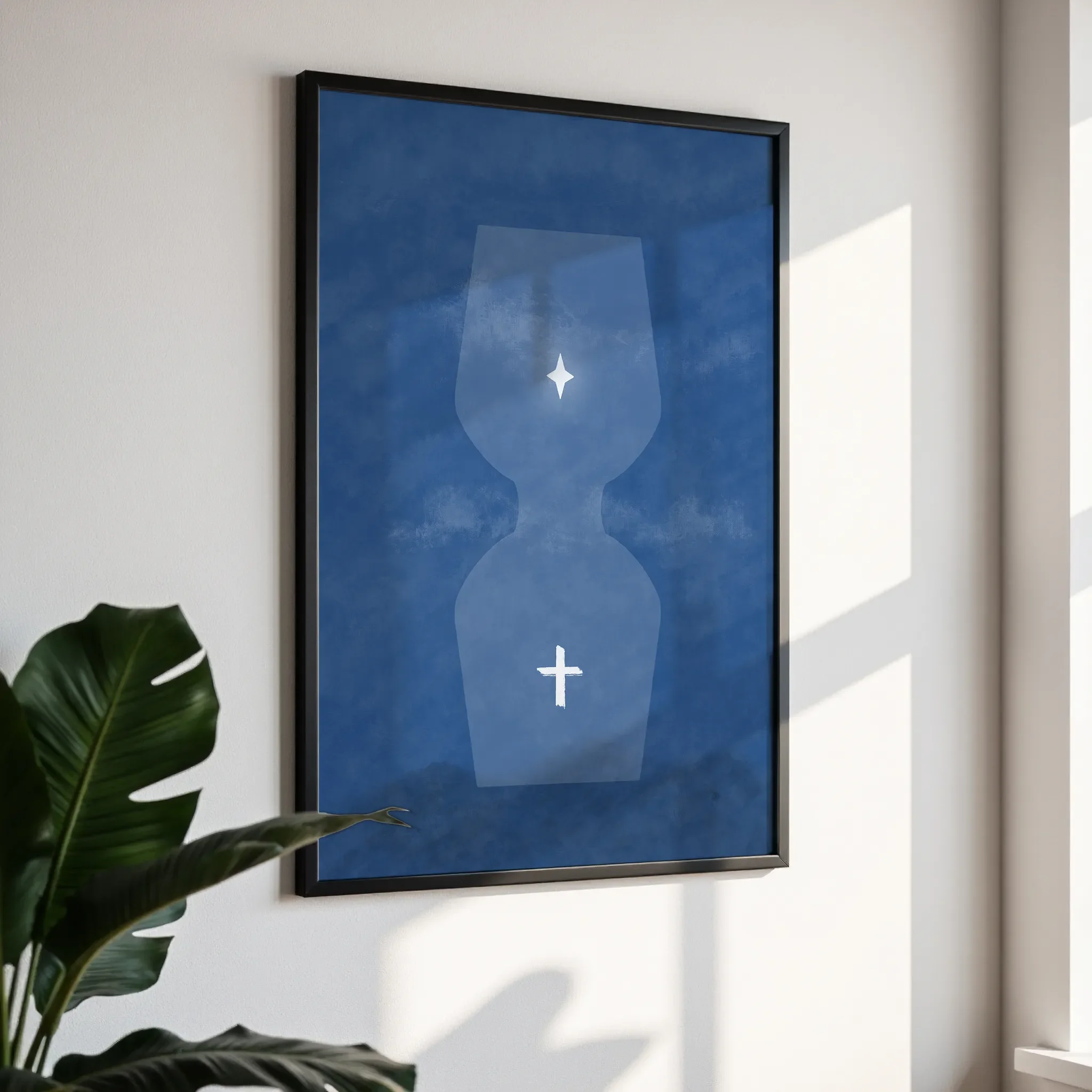 Framed wall art in a simple black frame, photographed from an angled view against a white wall with direct sunlight.