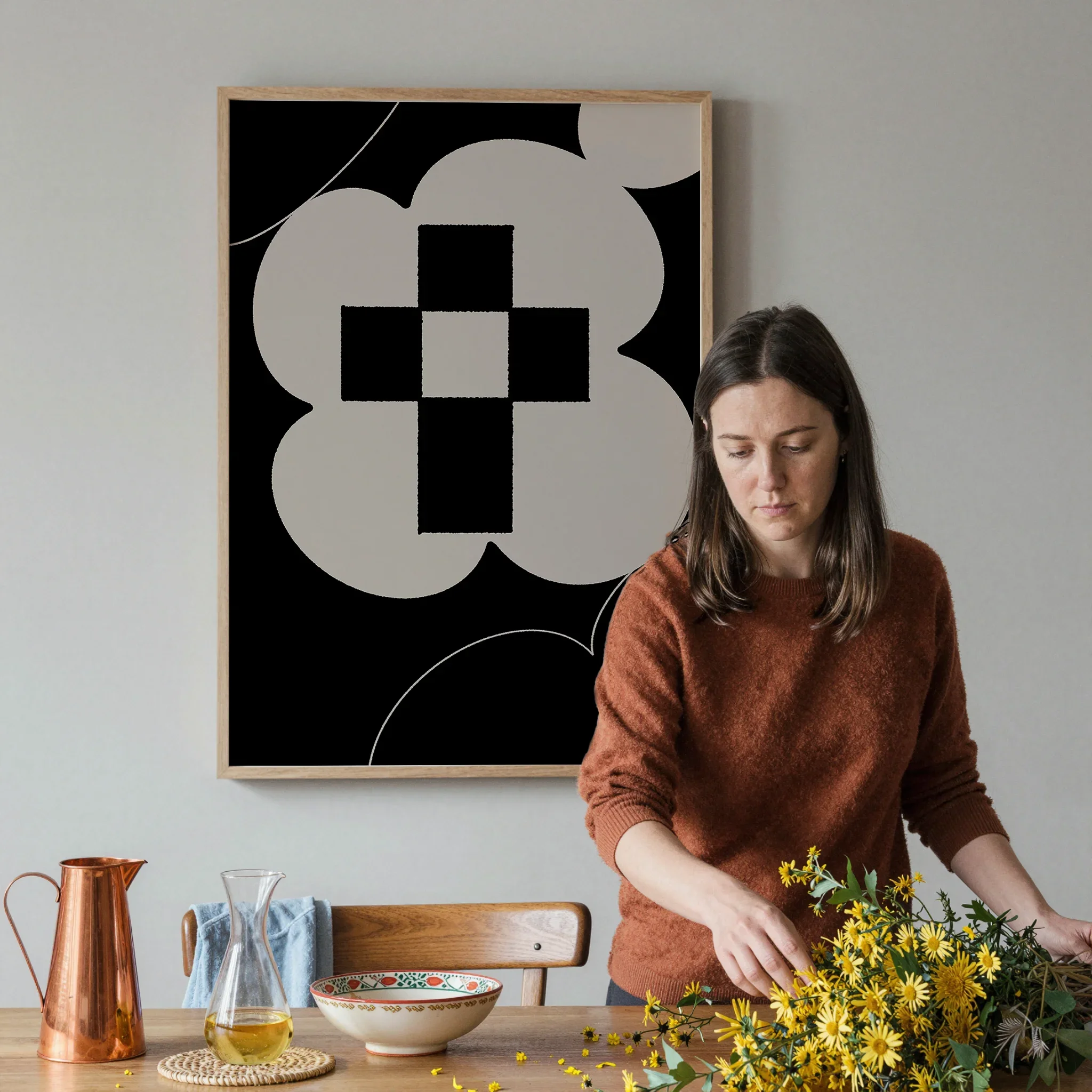 A Christian wall art print featuring cross art poster gentle floral design, shown in a dining space with a person arranging the table with flowers and tableware.