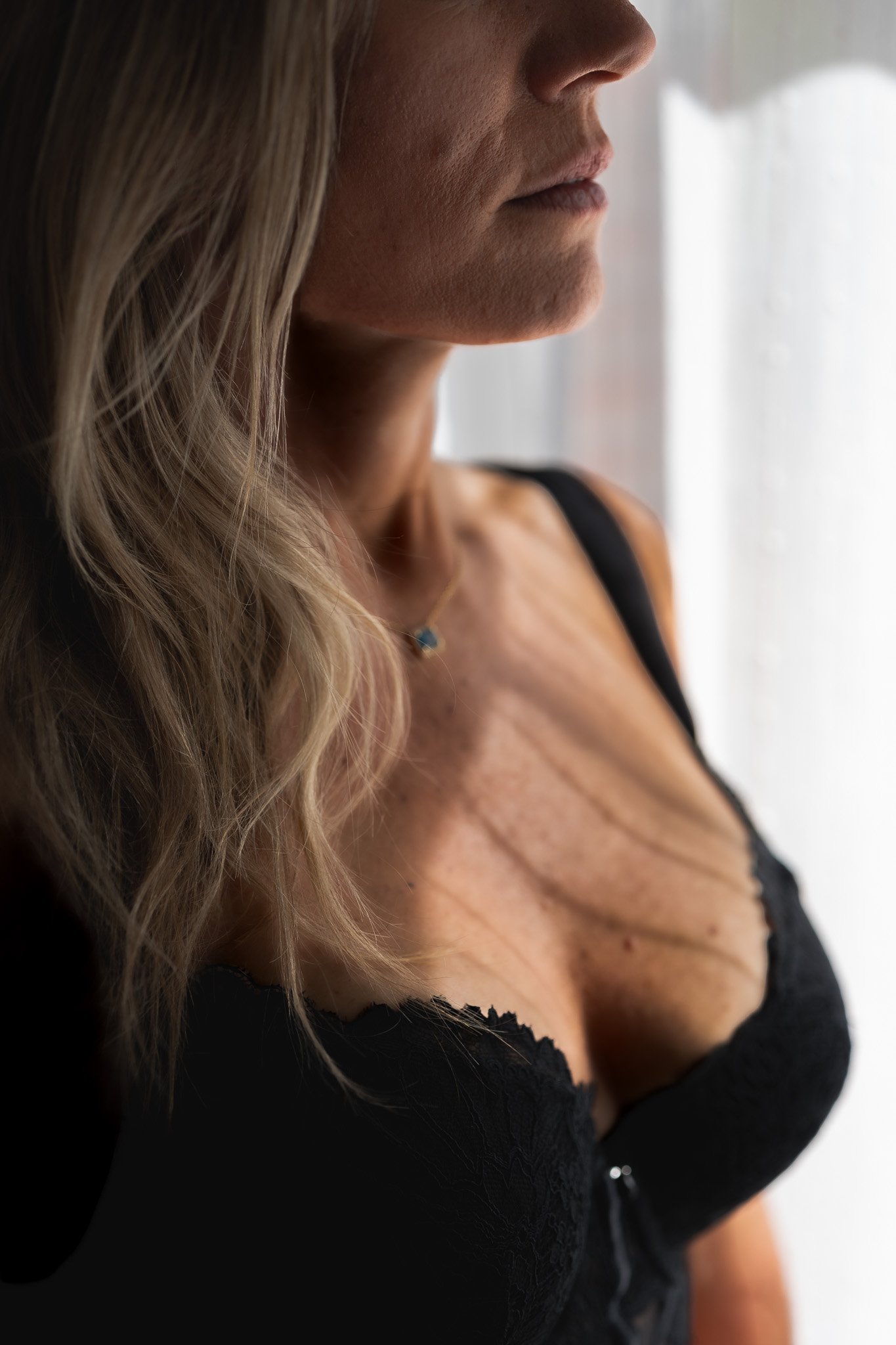 vrouw in lingerie voor een raam met zacht licht in boudoir stijl