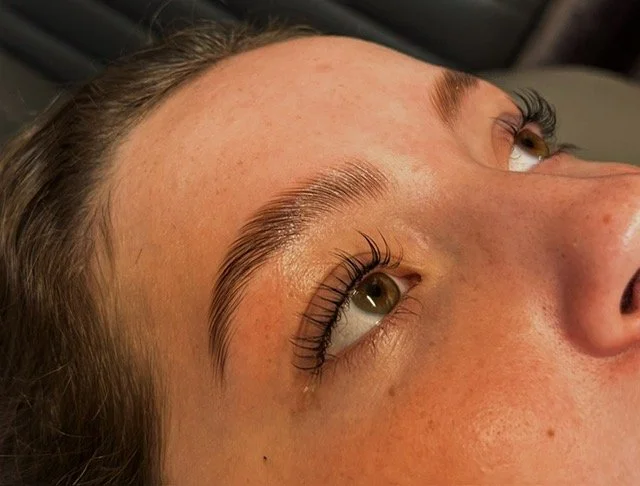 Close-up of a person's face, focusing on their eye and eyebrow, with long eyelashes and well-groomed eyebrows.