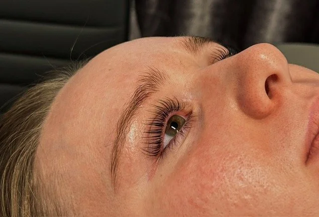 Close-up of a person's face lying down, focusing on the eye with long, curled eyelashes.