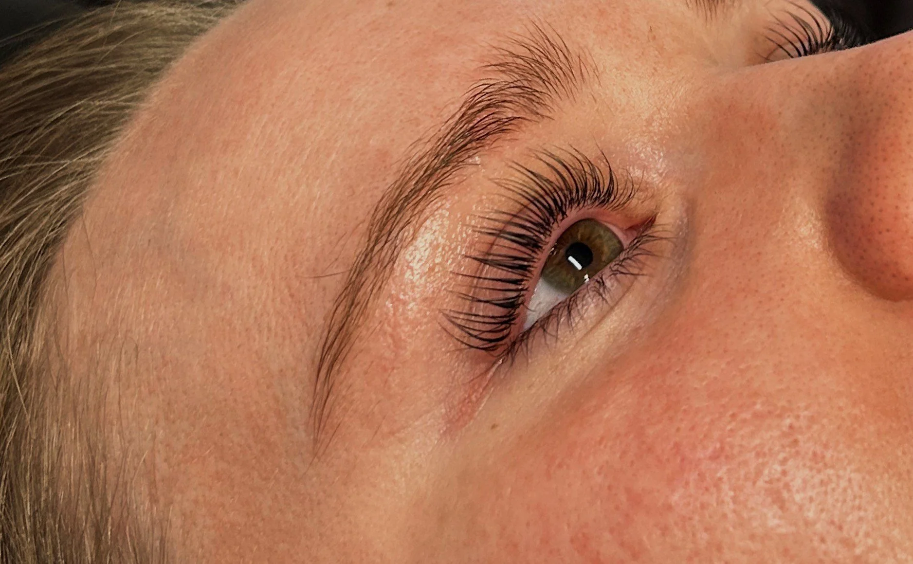 Close-up of a woman's face focusing on her eye, eyebrows, and surrounding skin.