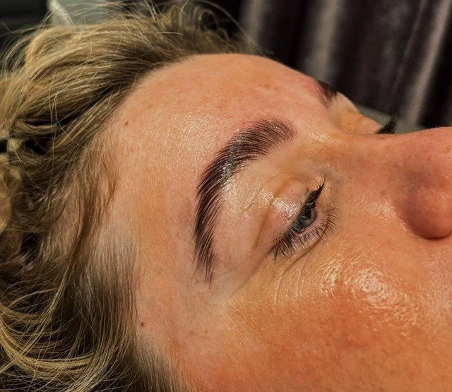 Close-up of a woman's face showing her eyebrow and eyelid, indicating she has recently had eyelash extensions or makeup applied.