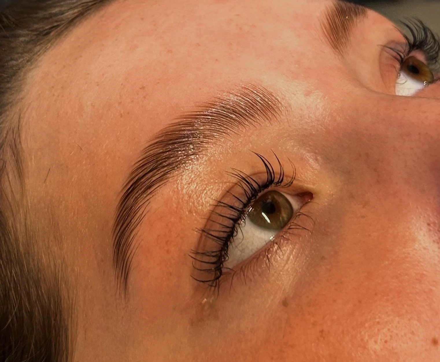 Close-up of a person’s face focusing on their eyebrow, eye, and lashes, with smooth skin and natural lighting.
