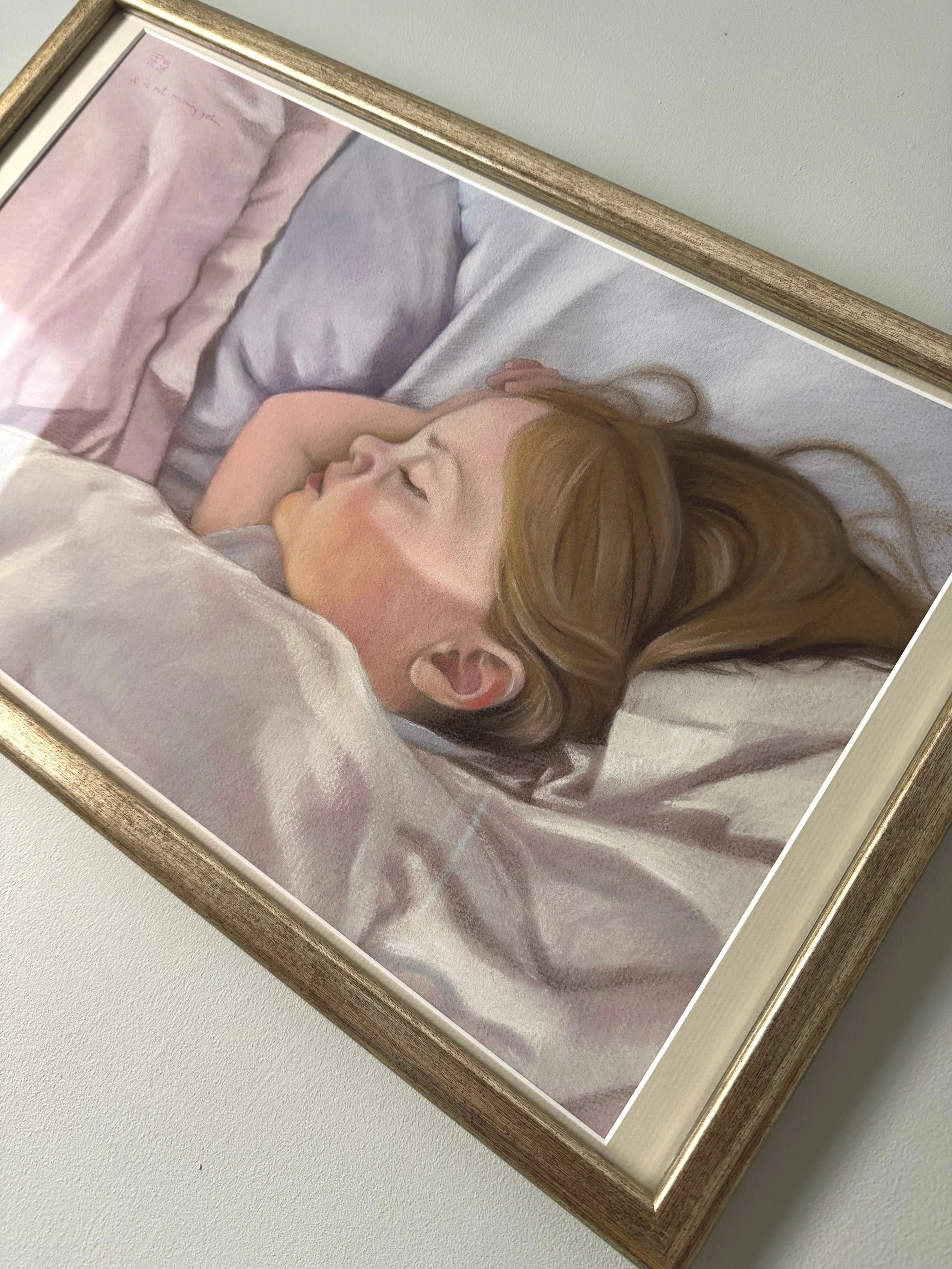 A framed painting of a woman sleeping on her side in bed, with her head resting on a pillow and her hand near her face, depicted in soft, realistic style.