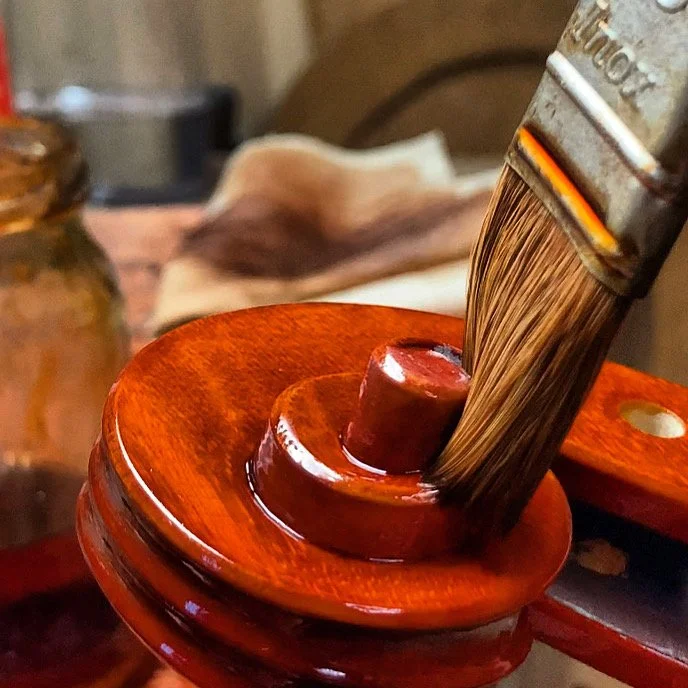 为手工制作的小提琴卷轴涂上清漆，作者：马可·奥西欧