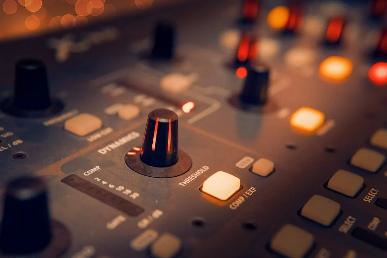 Close-up of a music mixing console showing various knobs and buttons, with a focus on the central black knob and a yellow button labeled 'GUMP / EXP.'