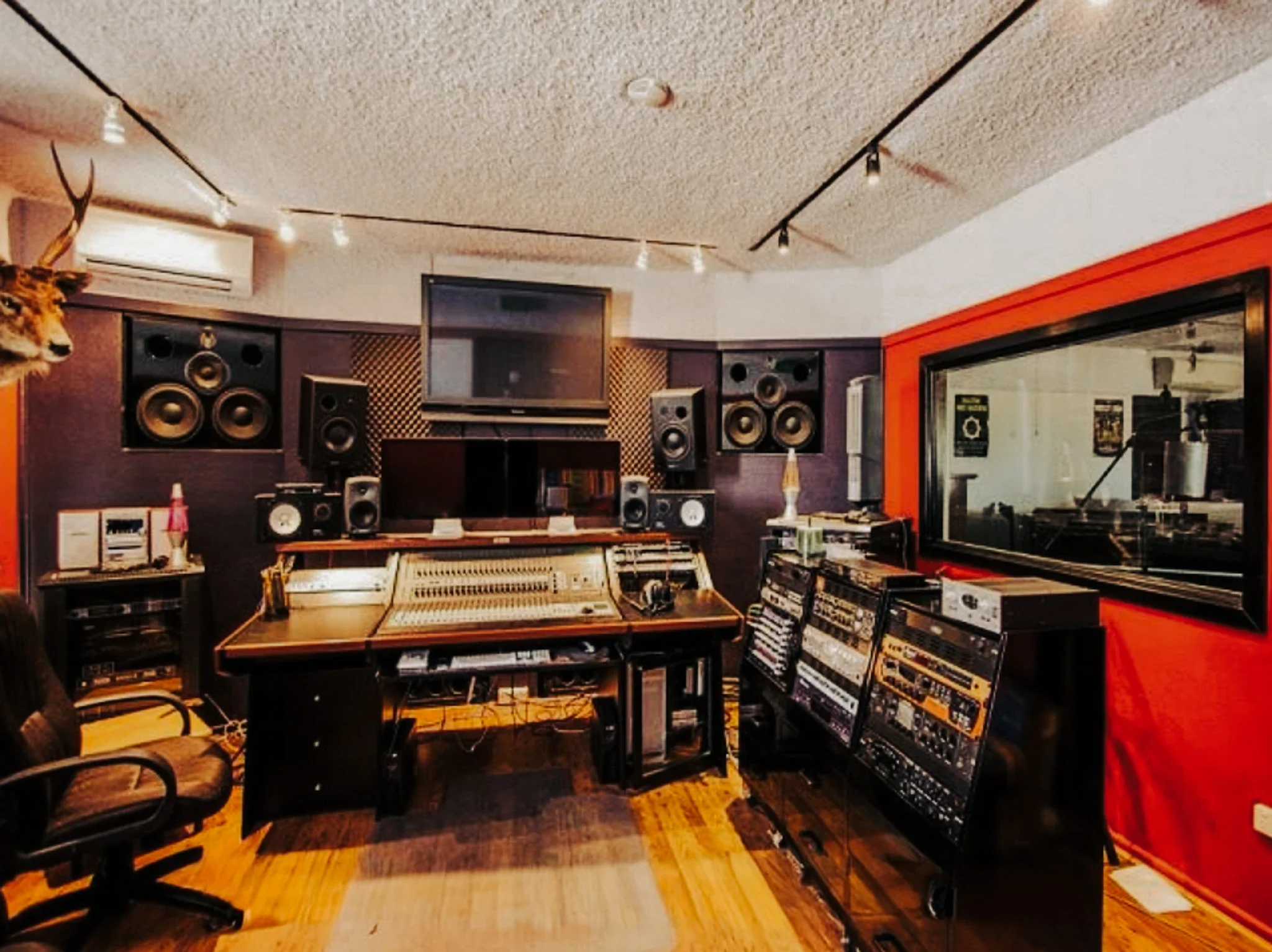Fat Track music recording studio with mixing console, studio monitors, and a large window to the recording booth.