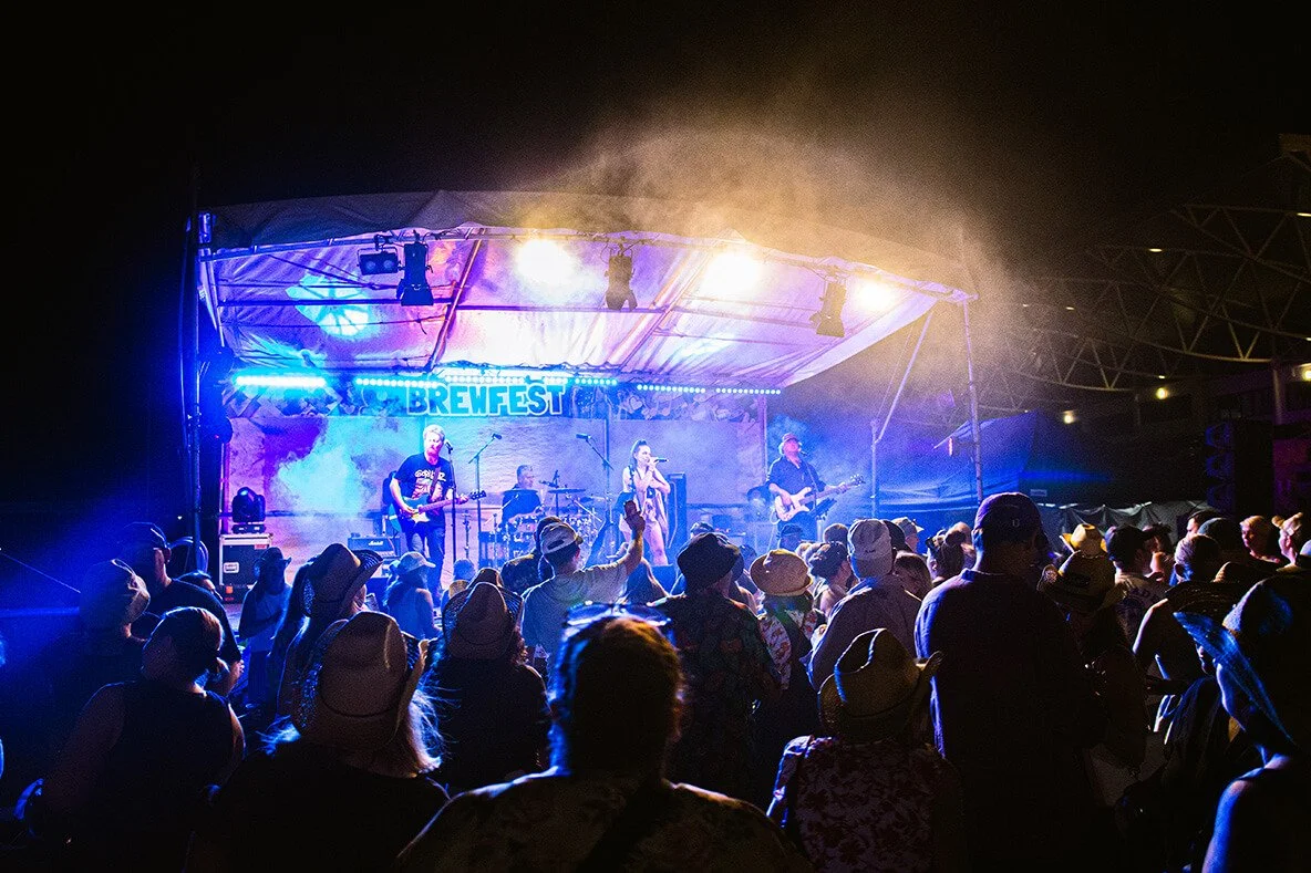 A live music performance at Brewfest with the band Savage Groover playing on stage and a large audience watching at night.