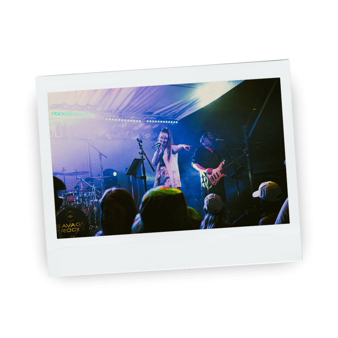 Polaroid picture of a band performing on stage with a singer and guitarist under colorful lights, audience members watching in the foreground.