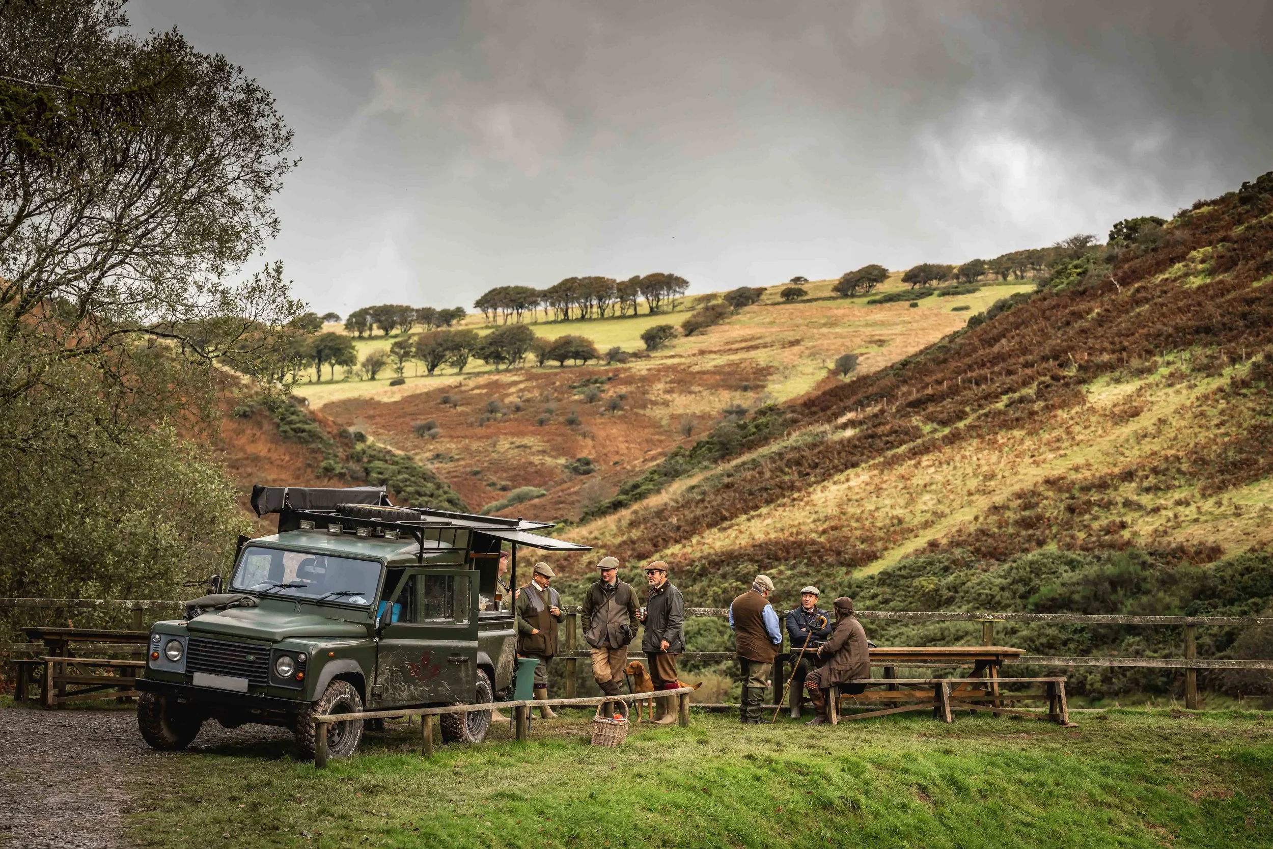 Guests standing by a Loyton Land Rover with picturesque Exmoor in the background.