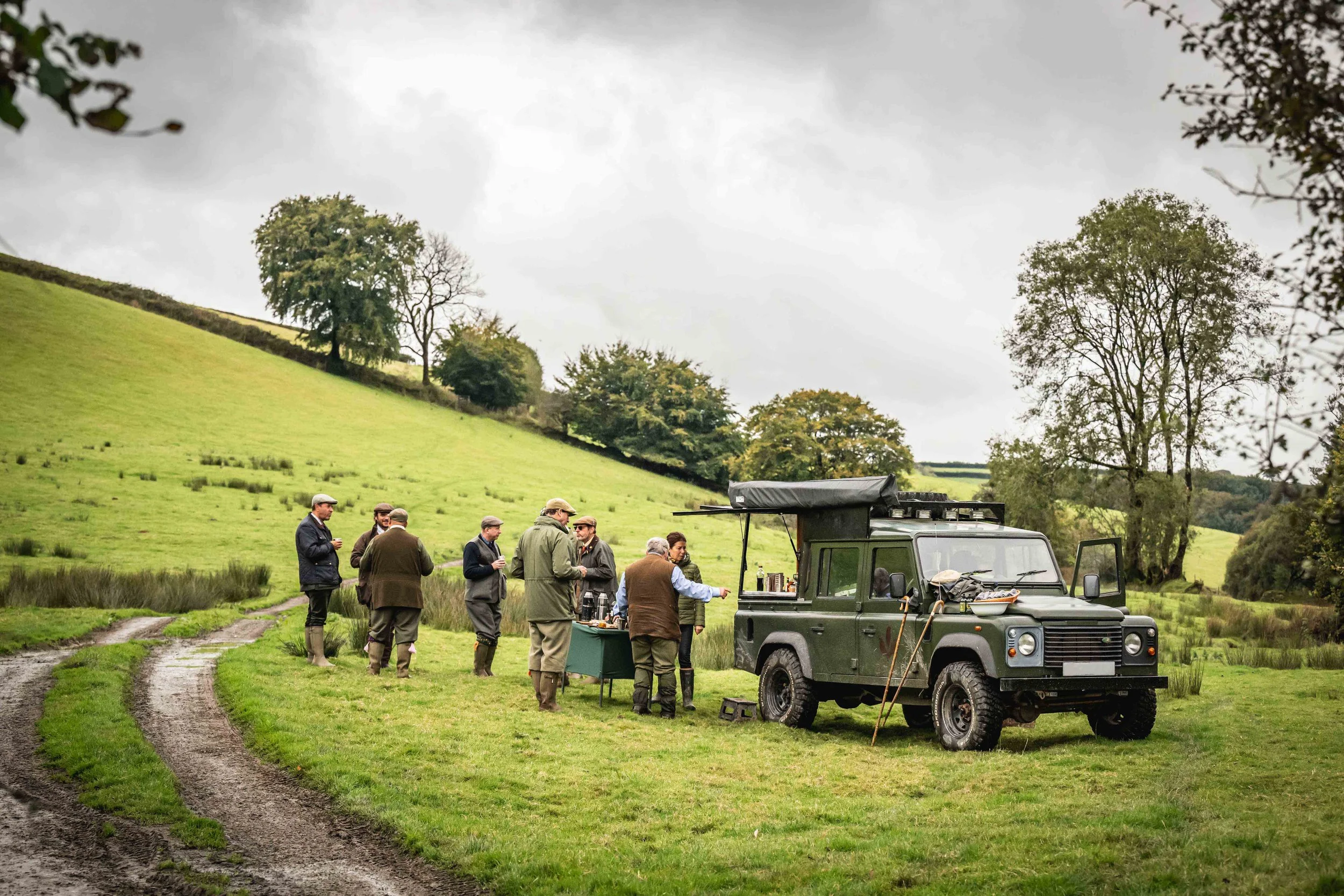 Guests enjoying refreshments from a Loyton Land Rover, parked in a field.
