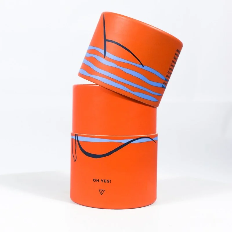 Bright orange luxury tube with blue and black print and partially removed lid, ideal for branded beauty packaging.